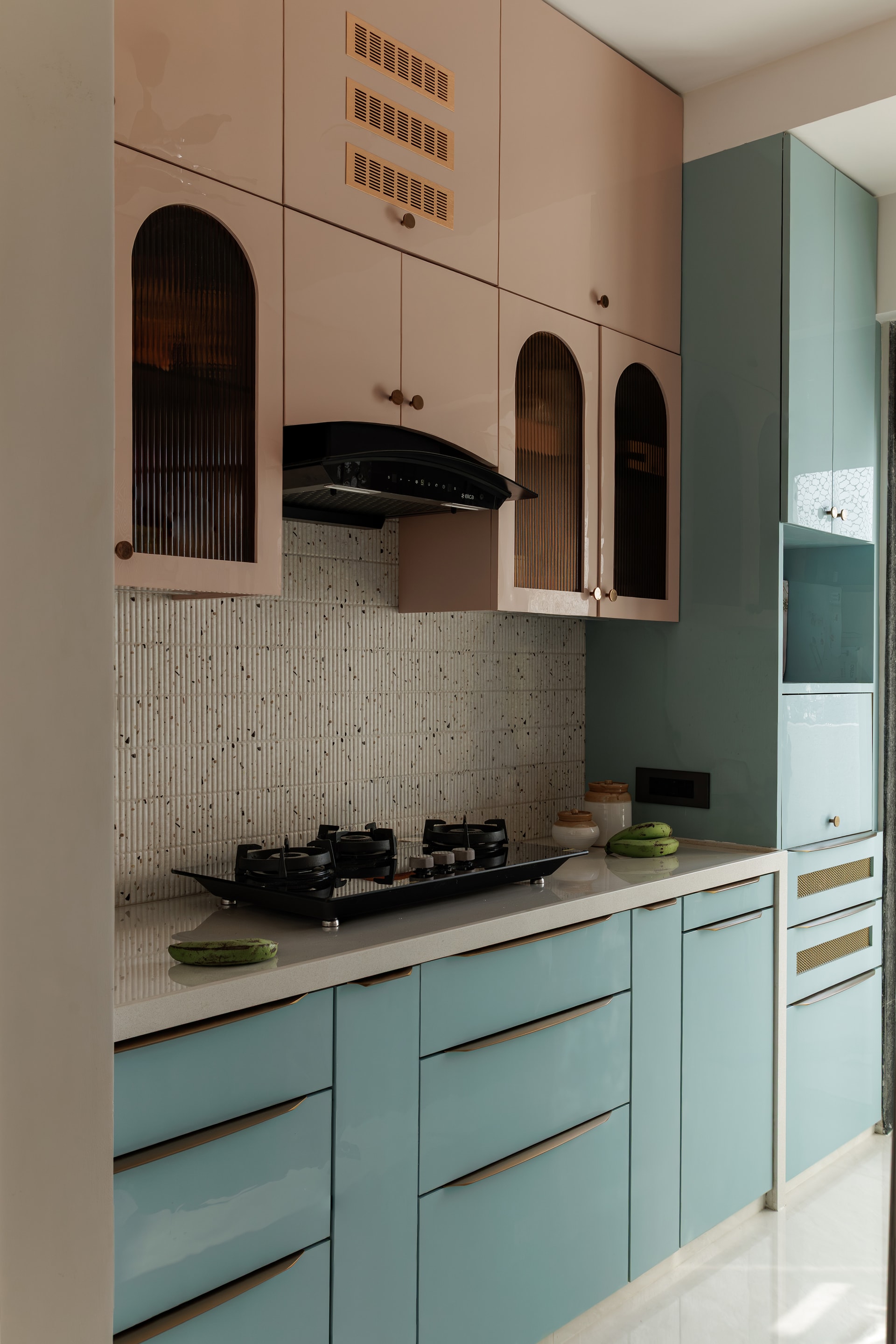 Pink and teal modular kitchen with arched glass cabinets and terrazzo backsplash