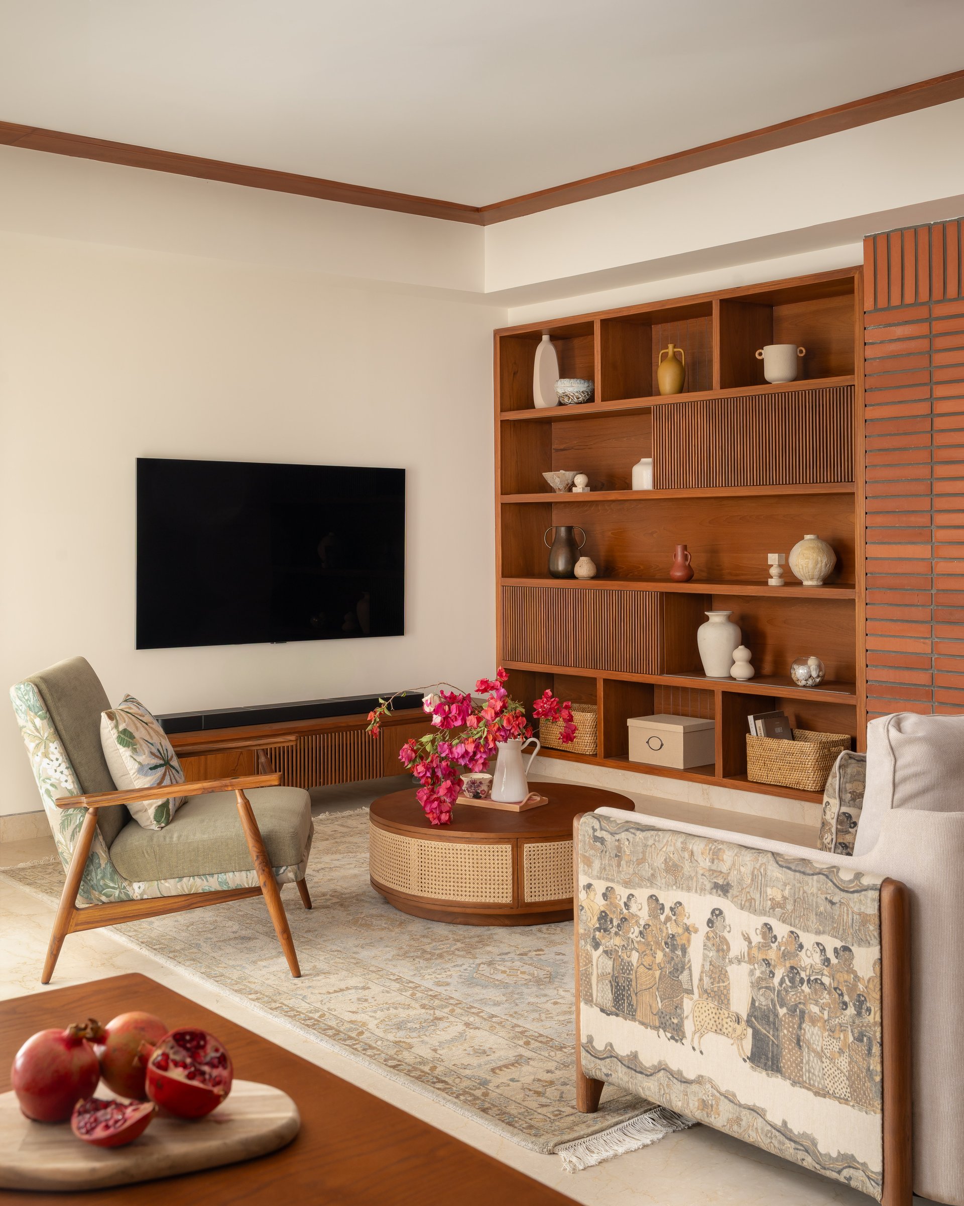 The full living room, where two differently upholstered armchairs around a cane-wrapped coffee table signal a home that has been collected rather than coordinated