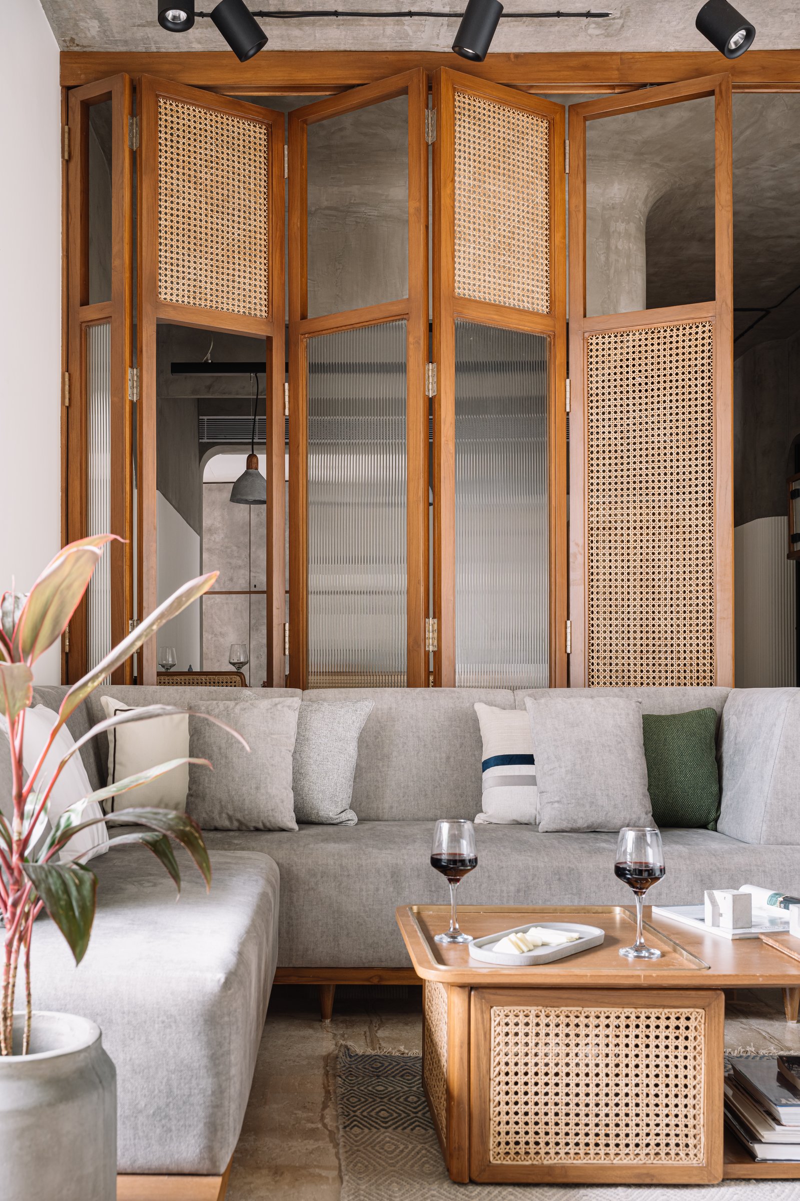 The folding partition in close-up, alternating woven cane and fluted glass panels within warm timber frames