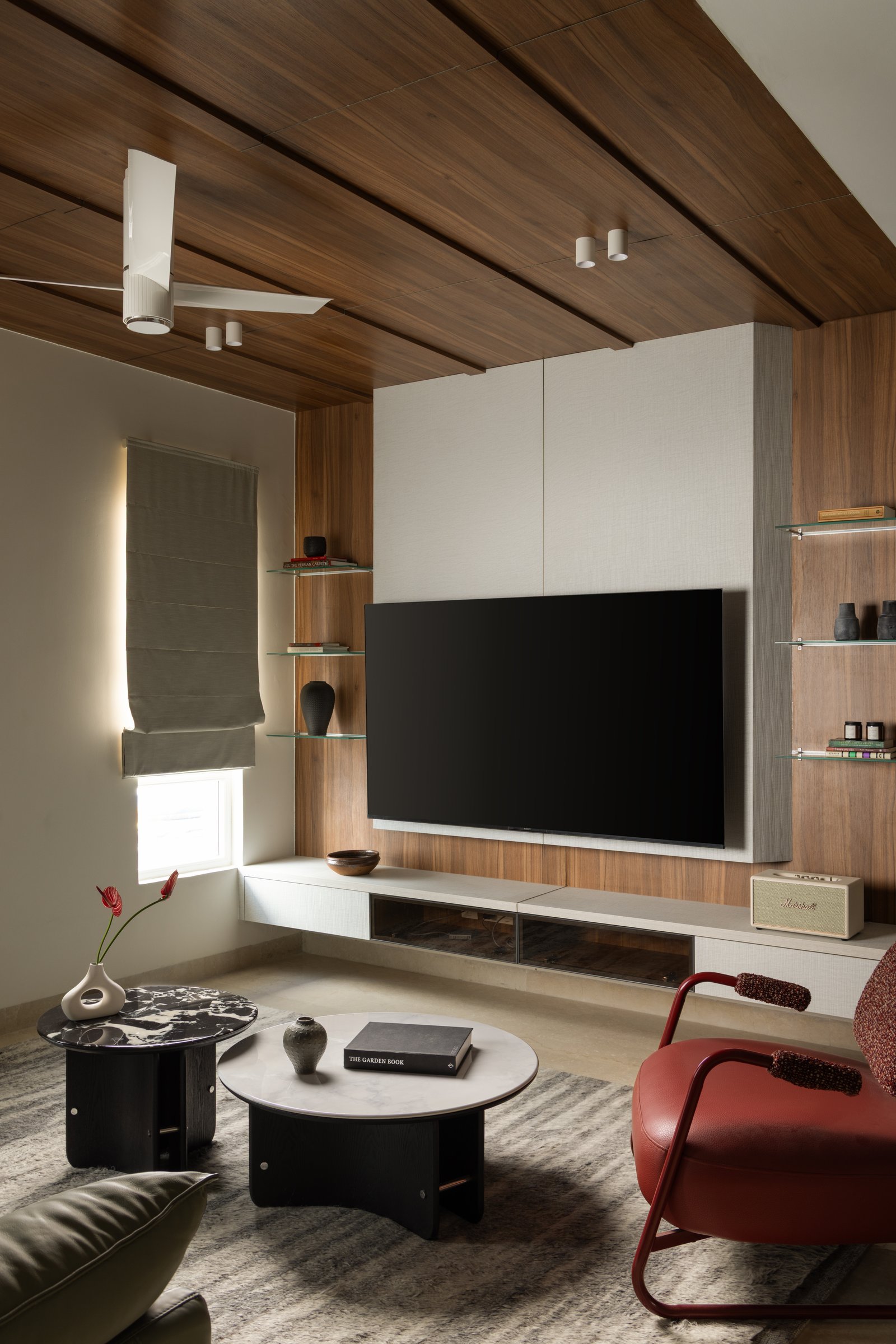 The informal living room, where wood panelling wraps ceiling and entertainment wall in a single immersive gesture