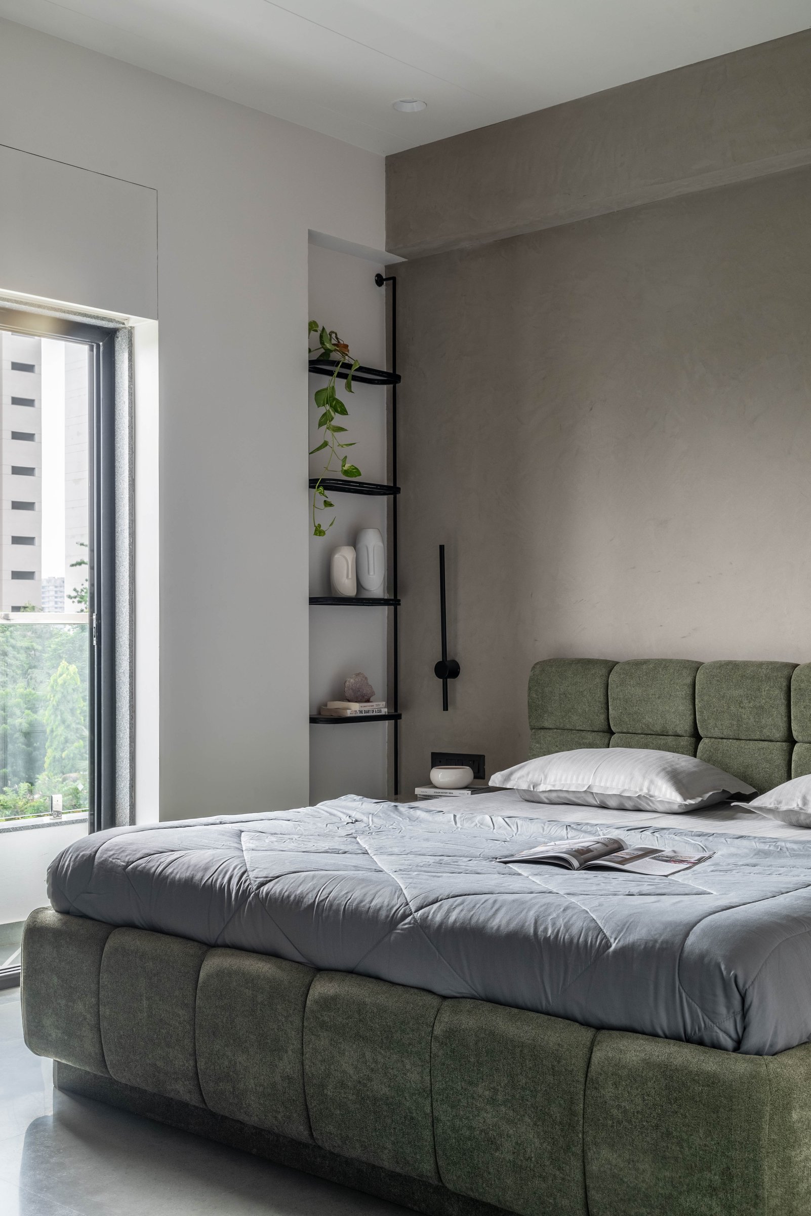 The master bedroom in muted olive and cement plaster, a deliberate shift from the living room's warmth