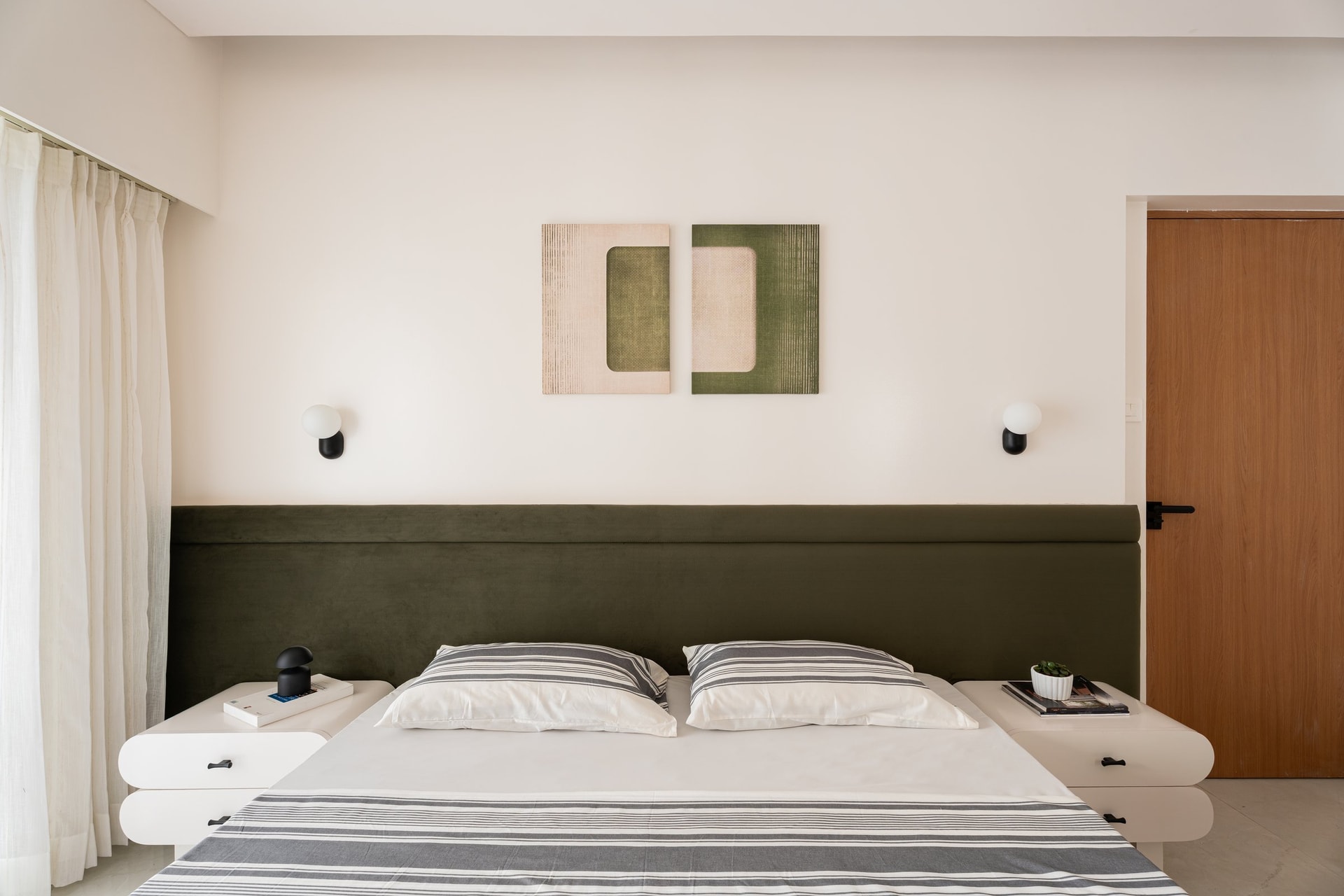 The master bedroom, anchored by an olive-green headboard that stretches the full width of the wall