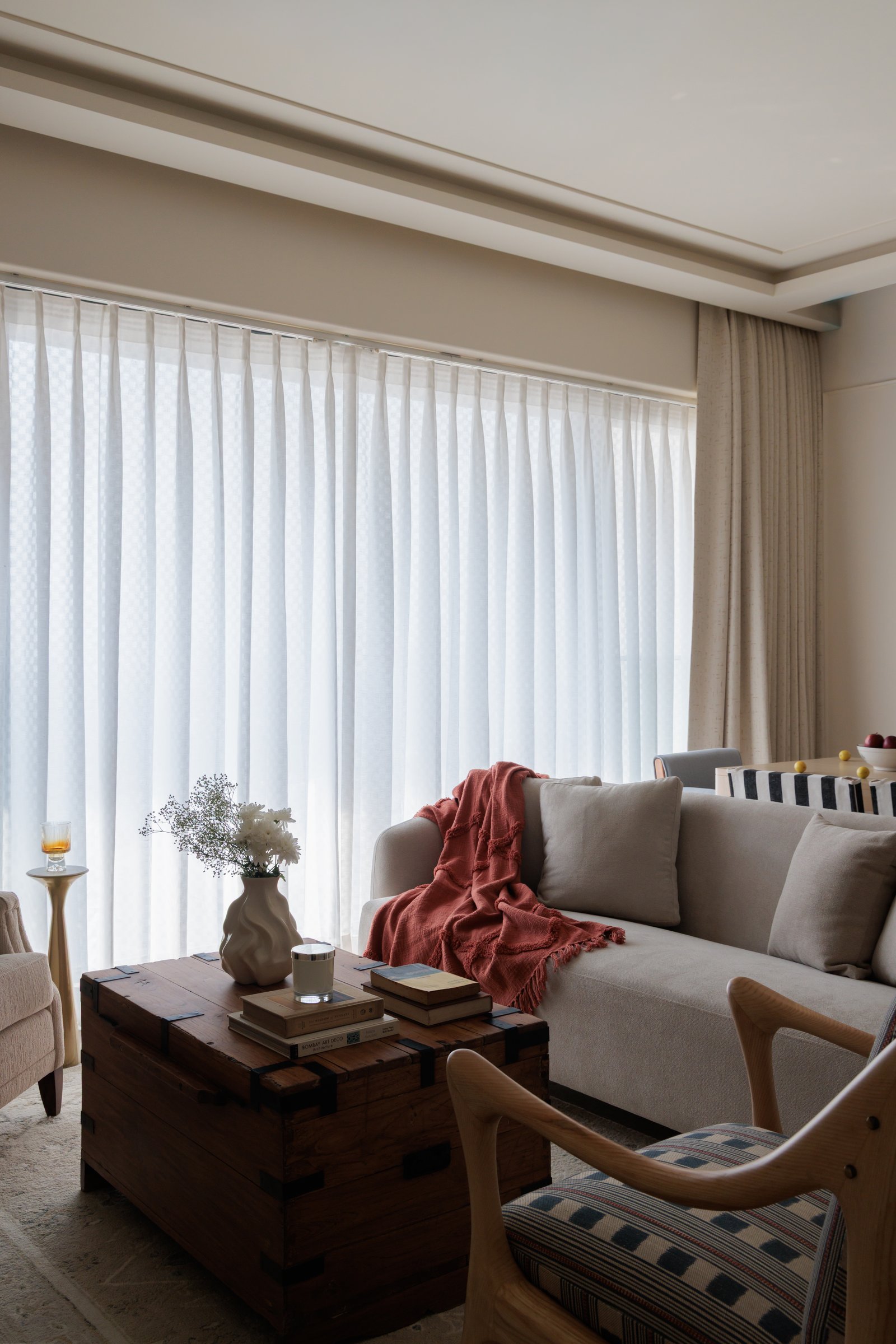 Sheer curtains across the full window wall let natural light dictate the living room's shifting mood