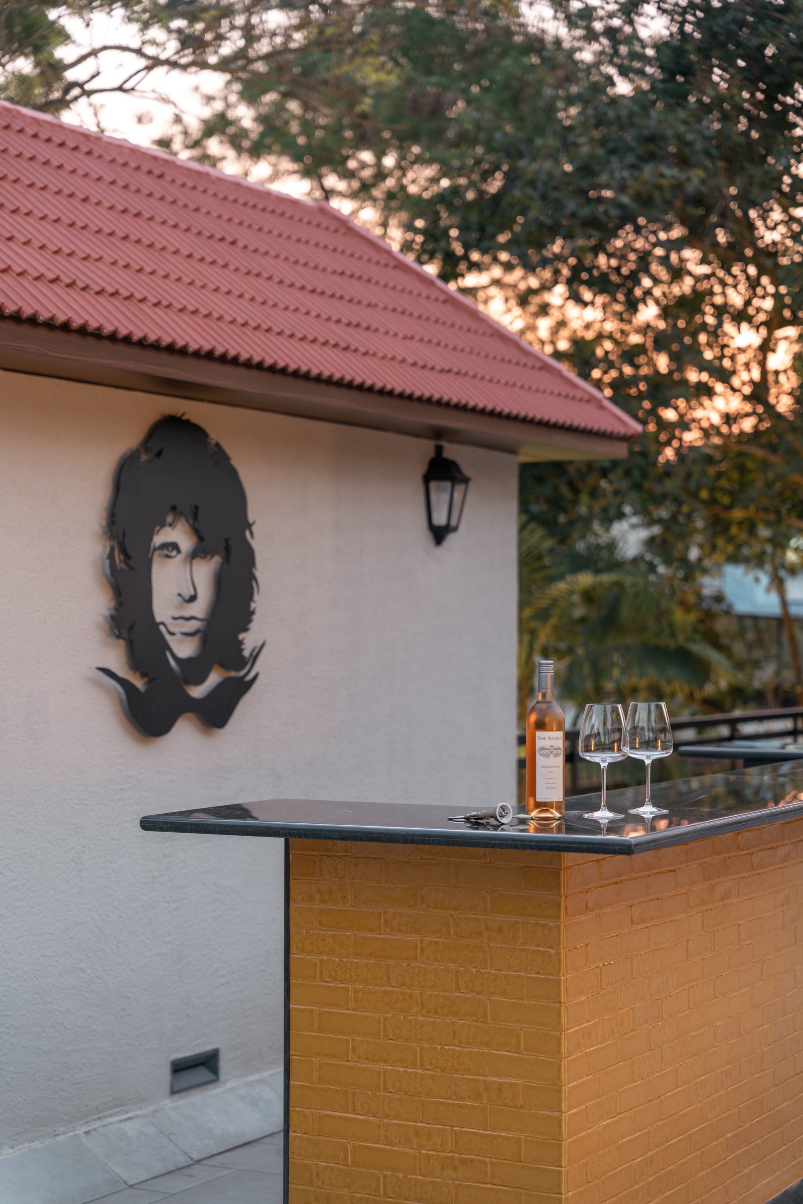 The outdoor terrace bar, where brick, dark stone, and a metal wall sculpture extend the home into the garden