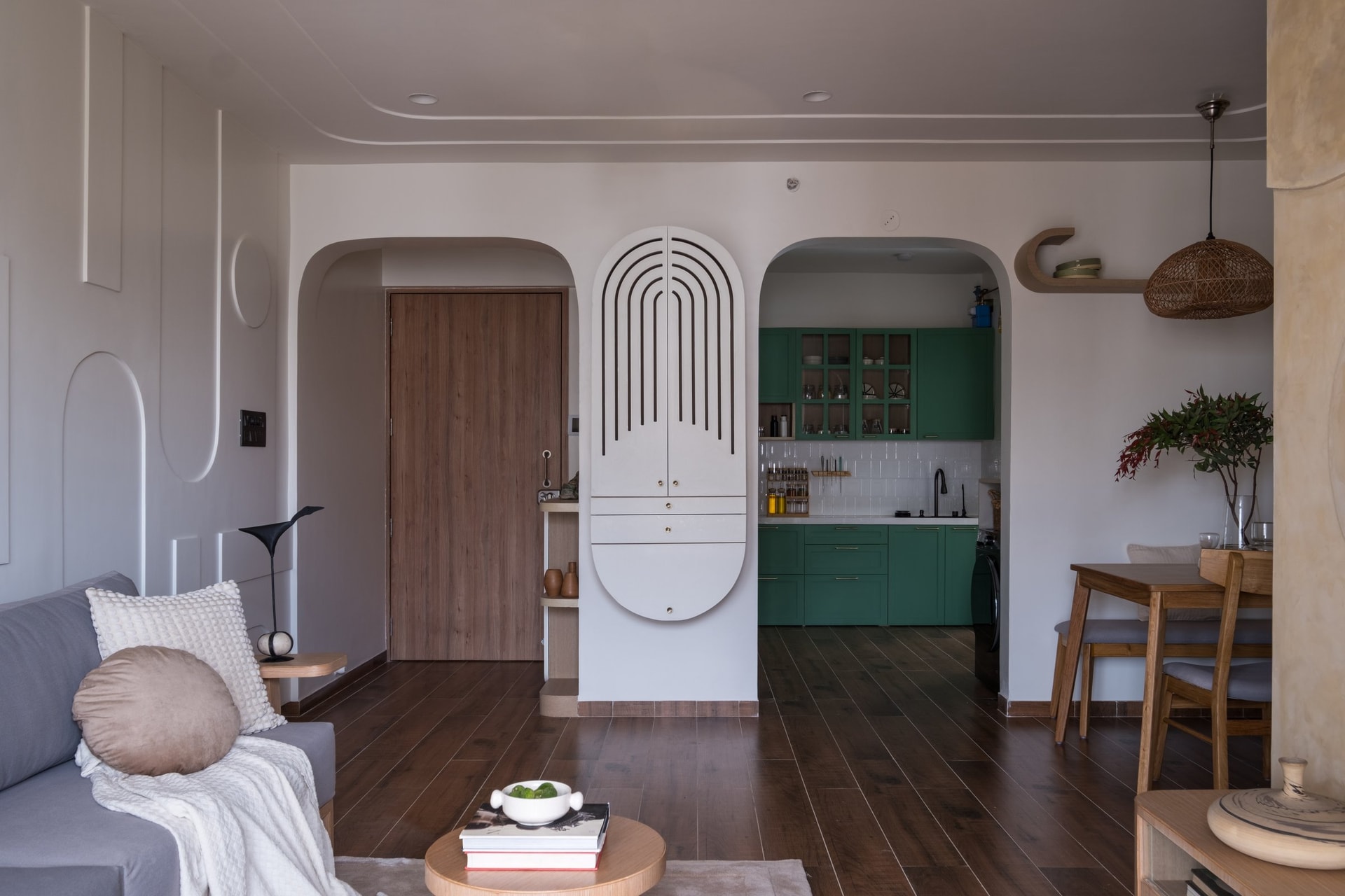 The threshold between living and kitchen, where a sculpted white storage piece announces the soft mint green beyond