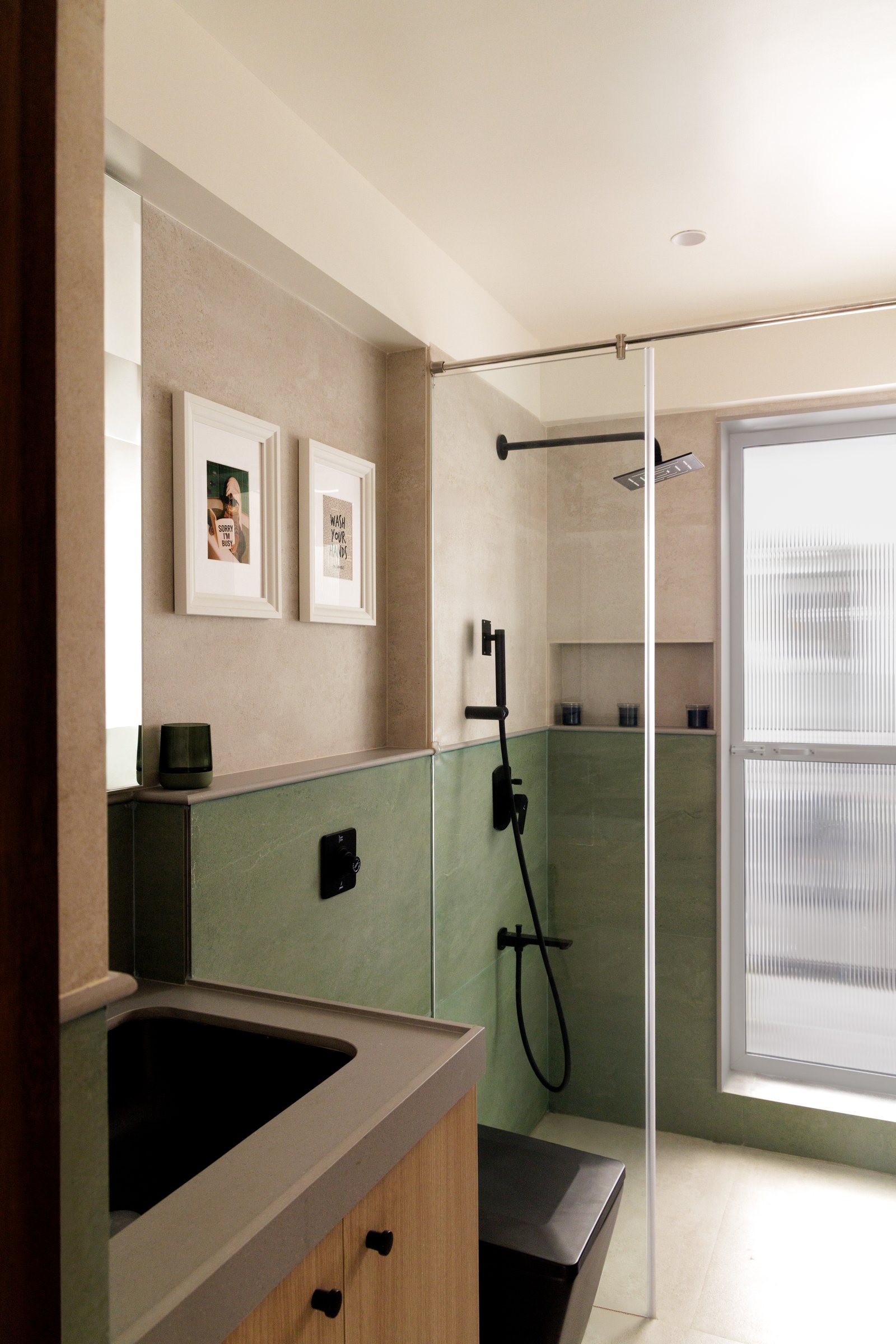 The first bathroom, where sage-green tile rises to dado height around the wet zone