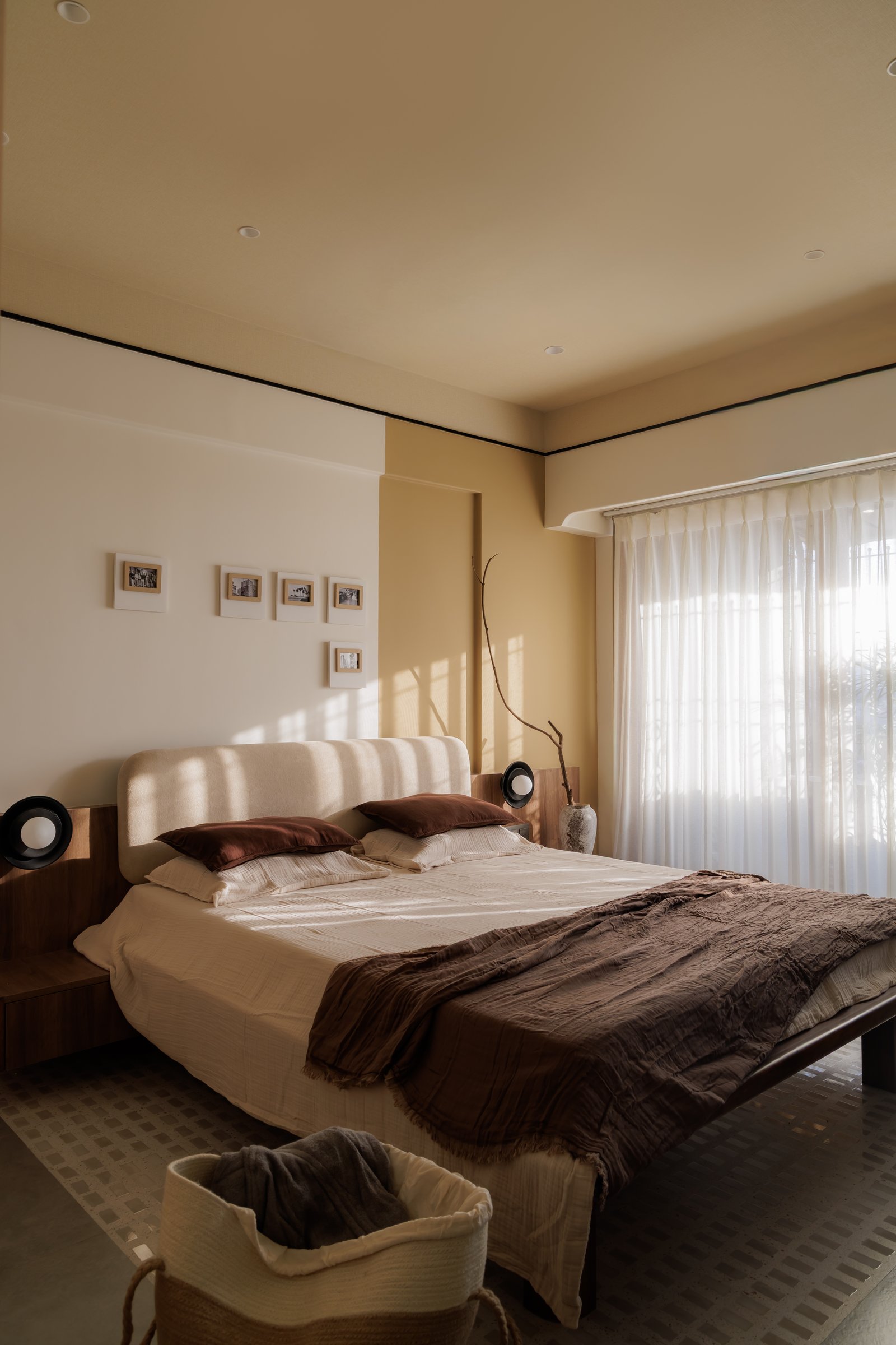 The master bedroom, divided between cream and ochre panels with a pale boucle headboard between them