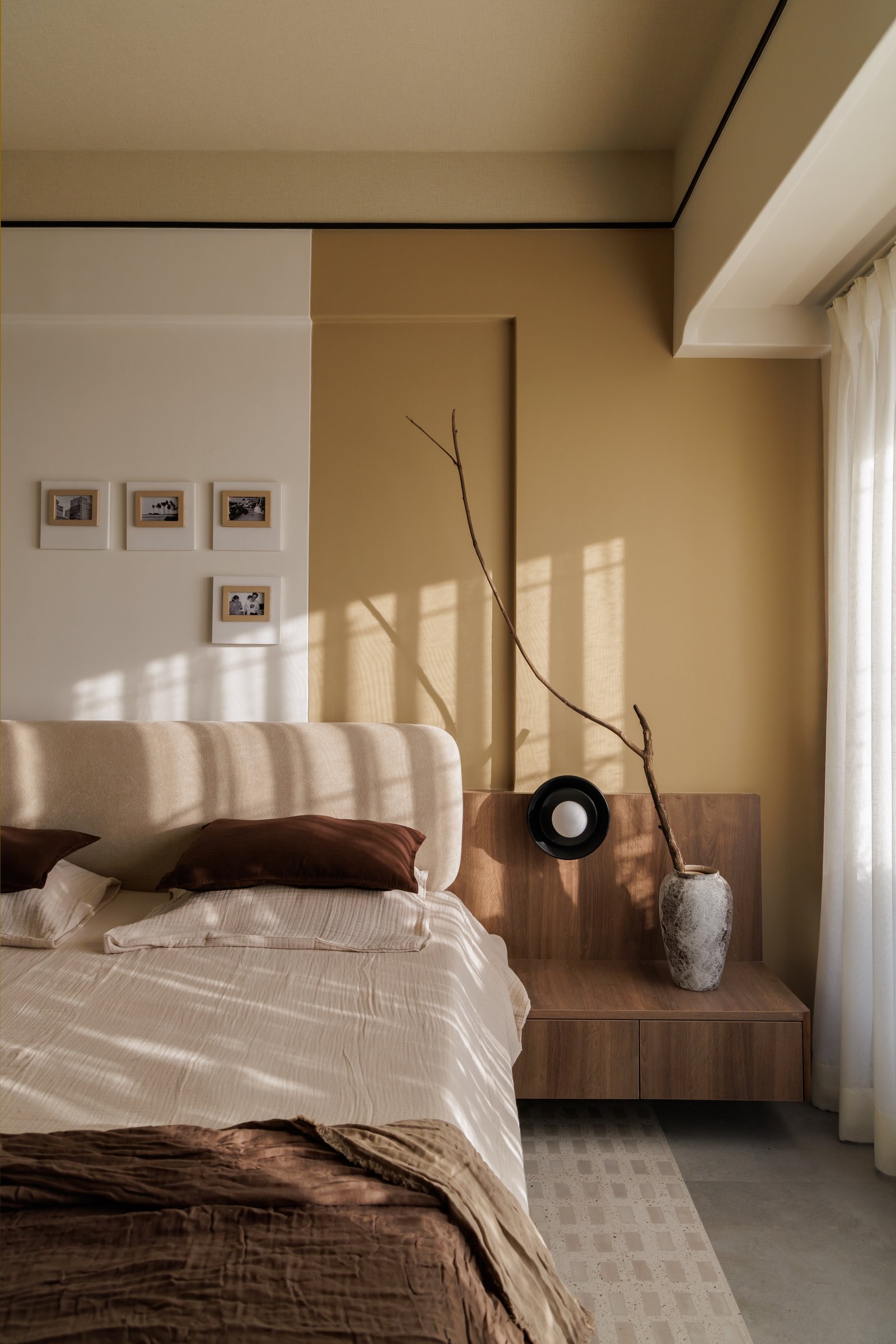 The ochre wall in afternoon light, paired with a stone urn and a bare branch