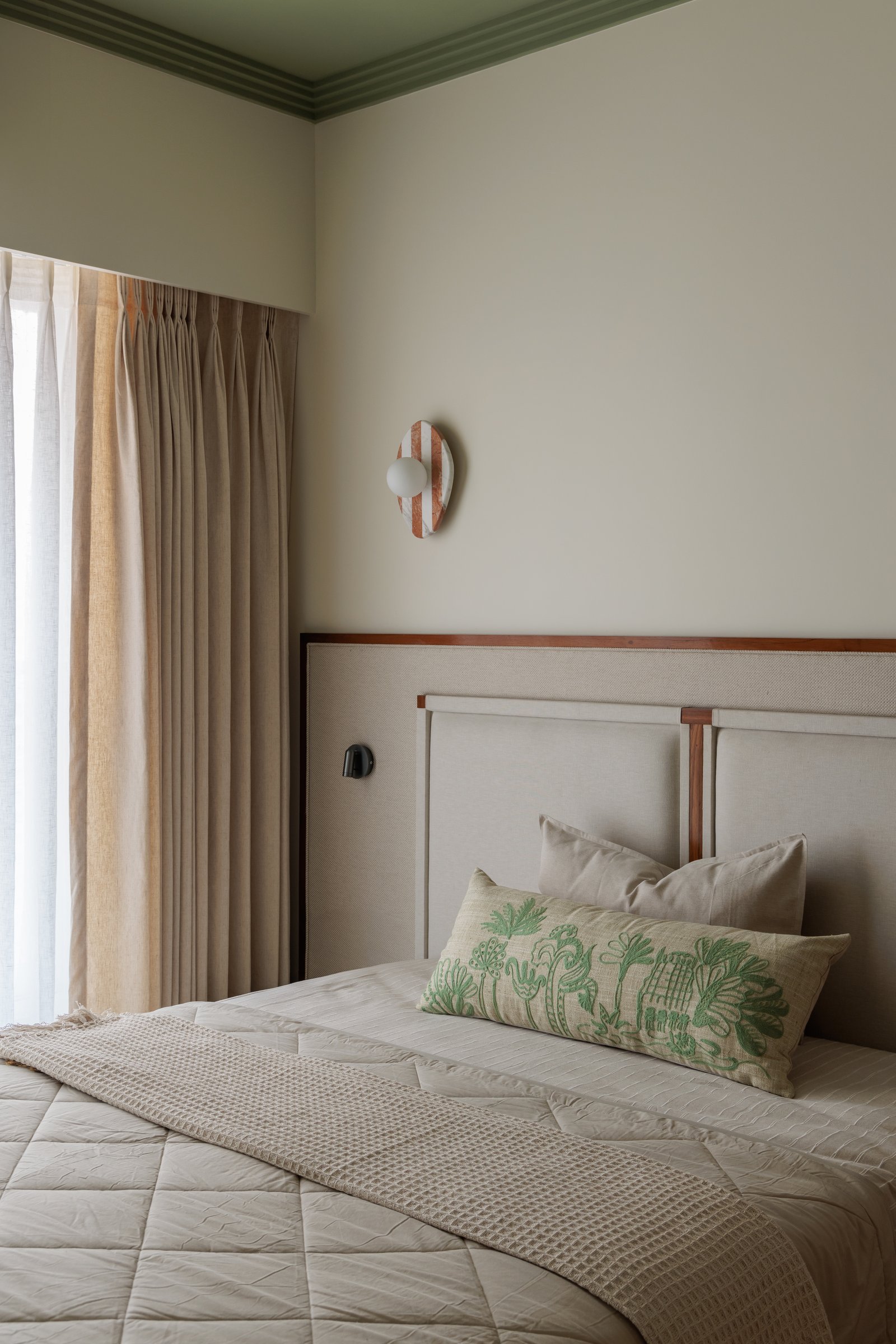 A sage-green painted ceiling and cornice give this bedroom an enveloping warmth distinct from the rest of the home