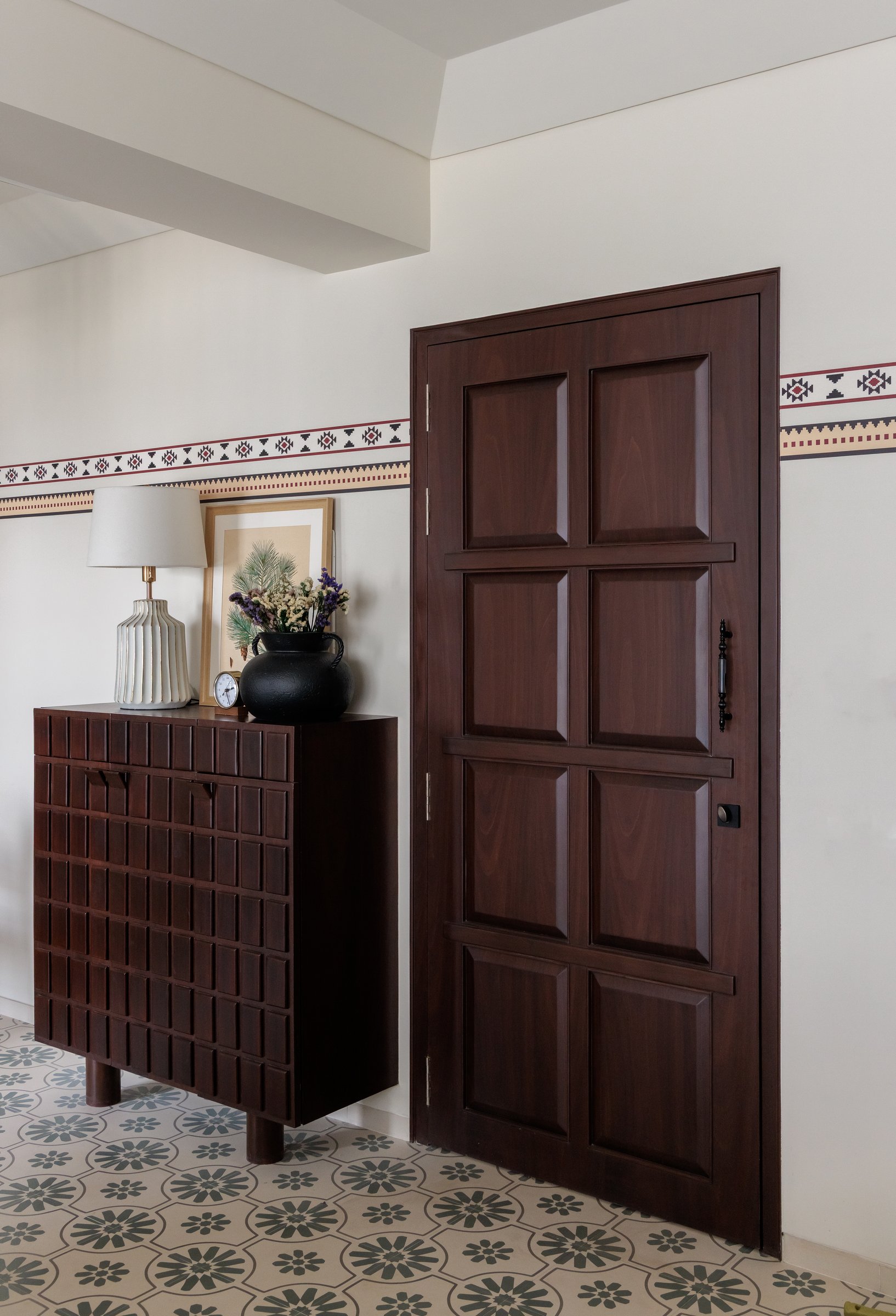 The entry: patterned cement tiles and a geometric wall border establish the home's decorative vocabulary from the threshold