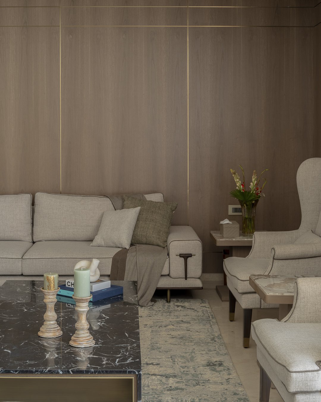 The living room, where warm timber and brass inlay hold the room in a single tonal register