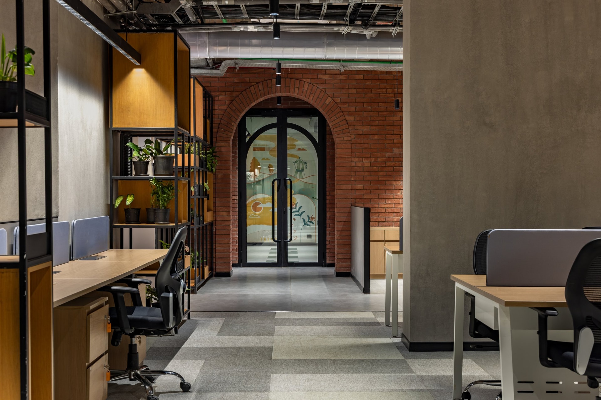 The open workspace, daylit and honest about its services, with the brick arch anchoring the far end