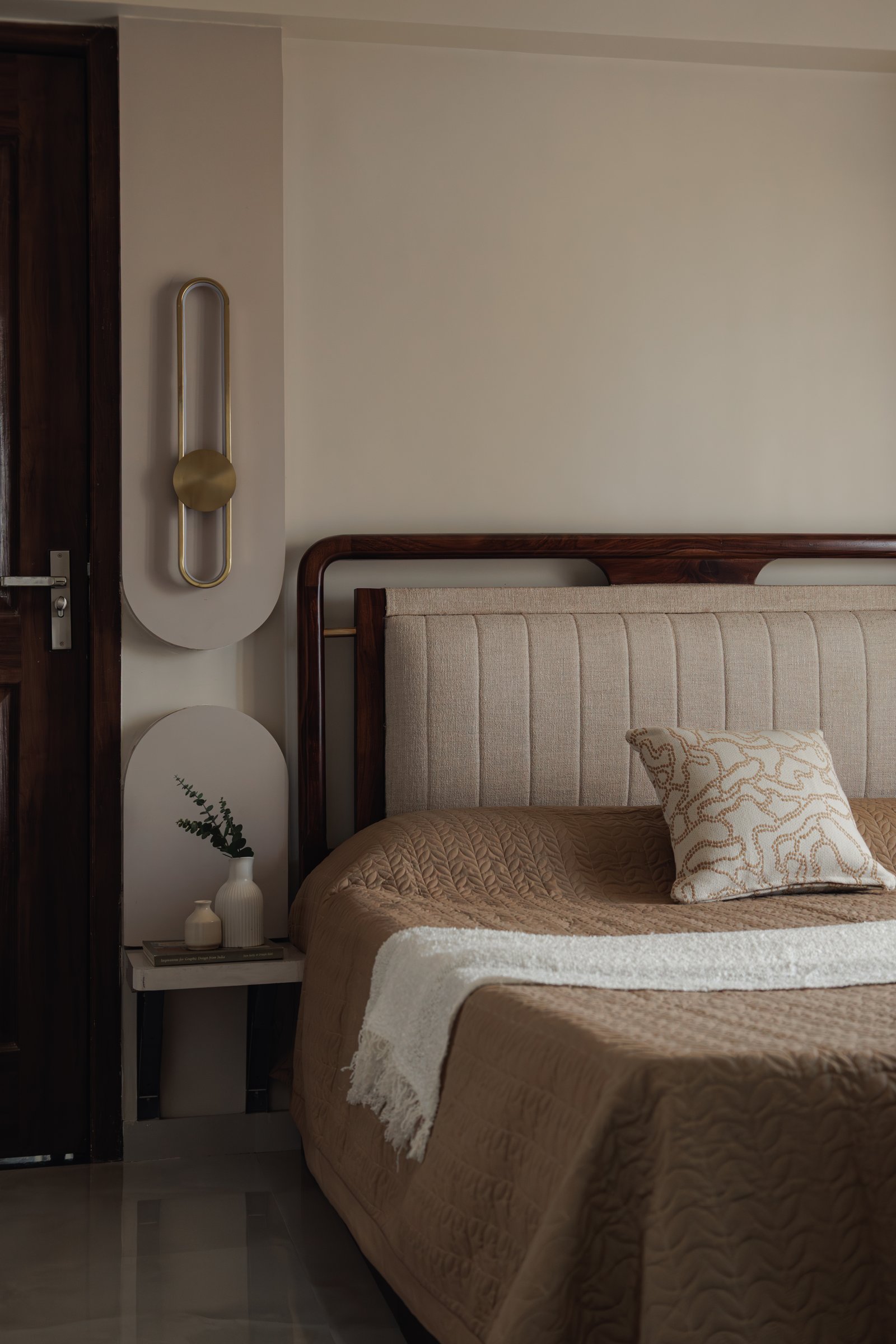 The master bedroom, where a walnut bedframe and linen-upholstered headboard set the slower register of the space