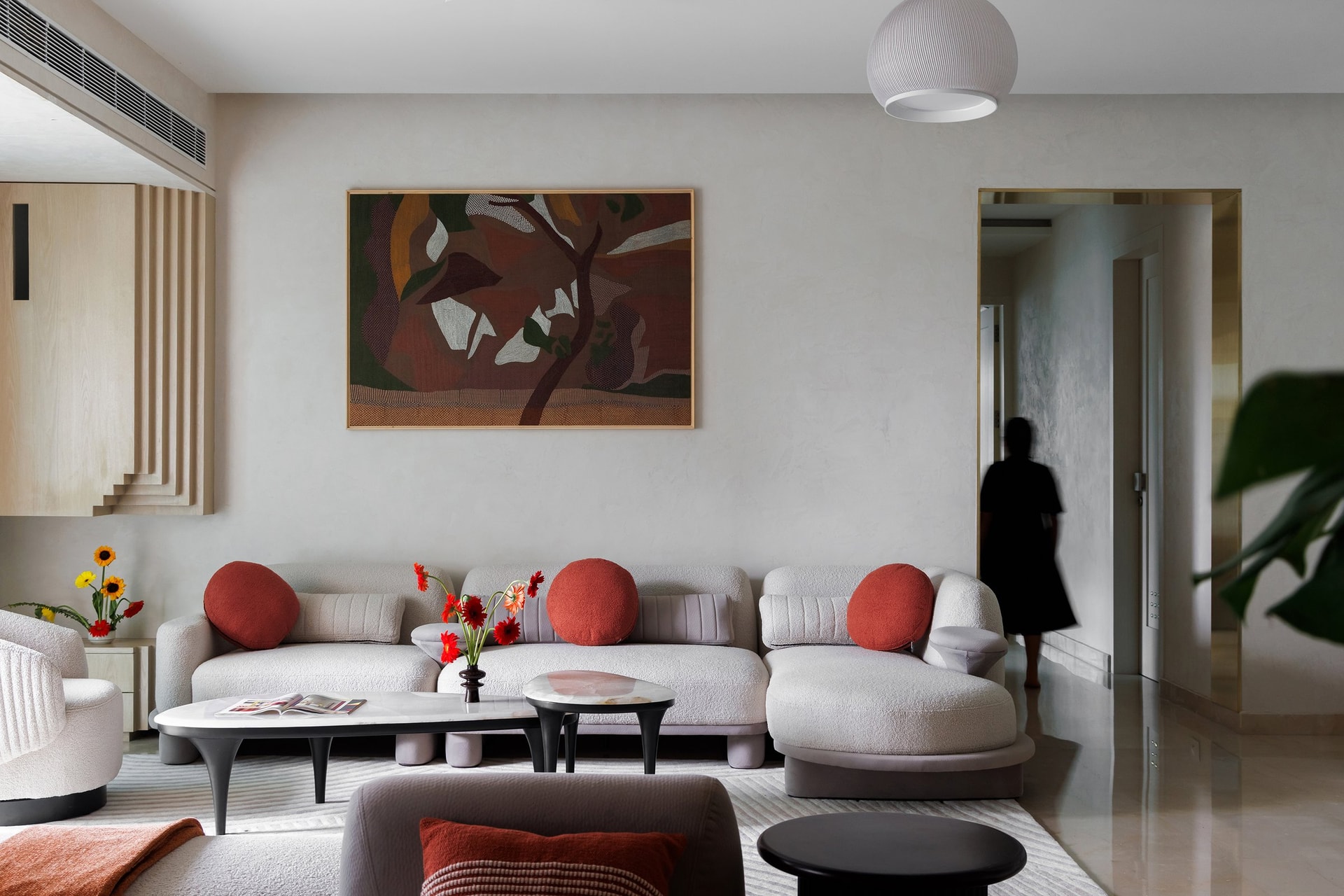 A long oatmeal boucle sectional with terracotta cushions; a single abstract canvas above replaces the gallery wall most homes would attempt