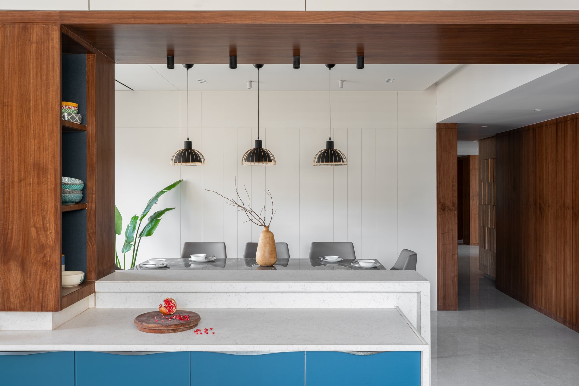 From the kitchen side, the breakfast counter steps down in stone, with the fluted dining backdrop concealing structural offsets