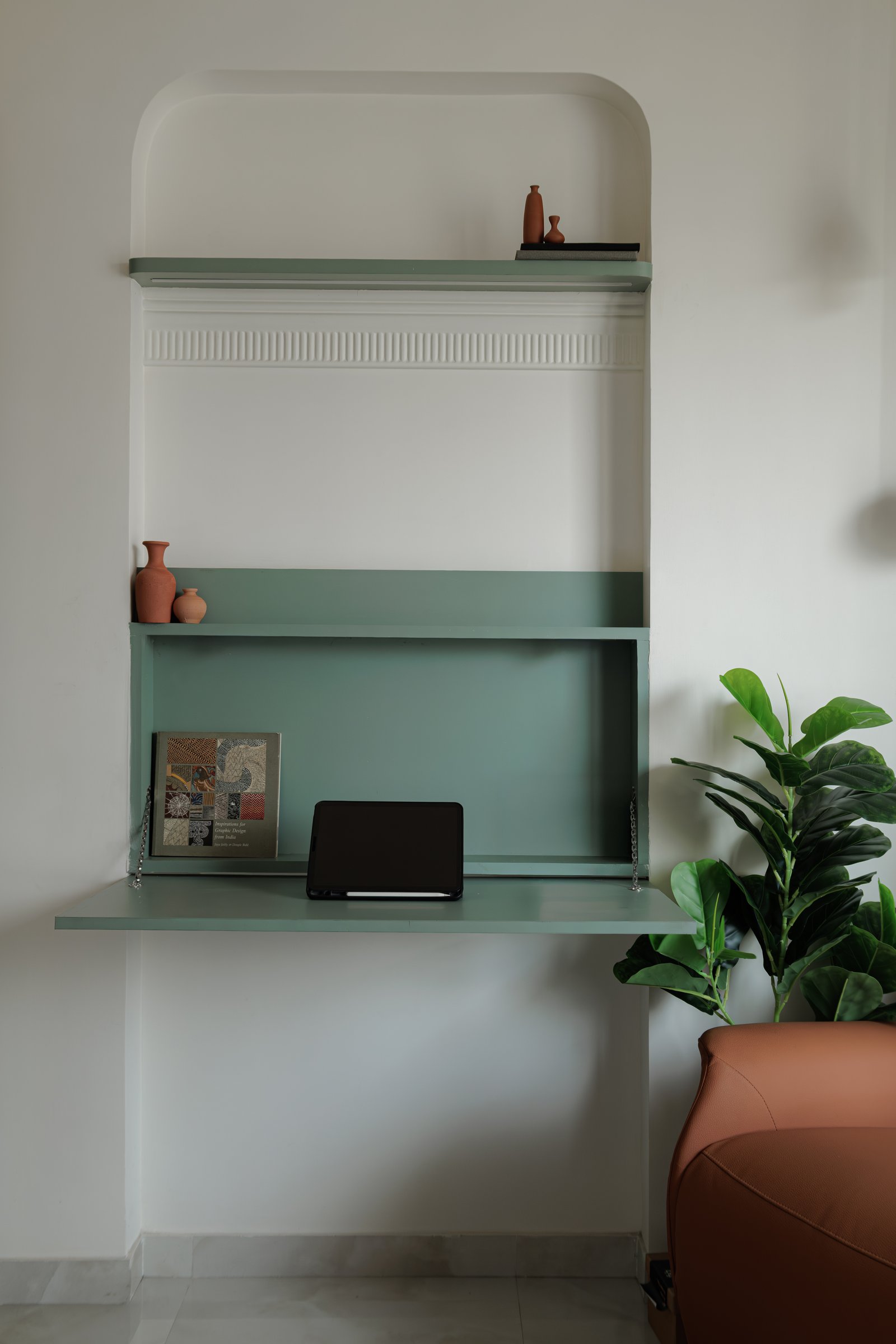 A fold-down work surface in sage green tucked into an alcove, the project's quiet answer to the small-apartment study