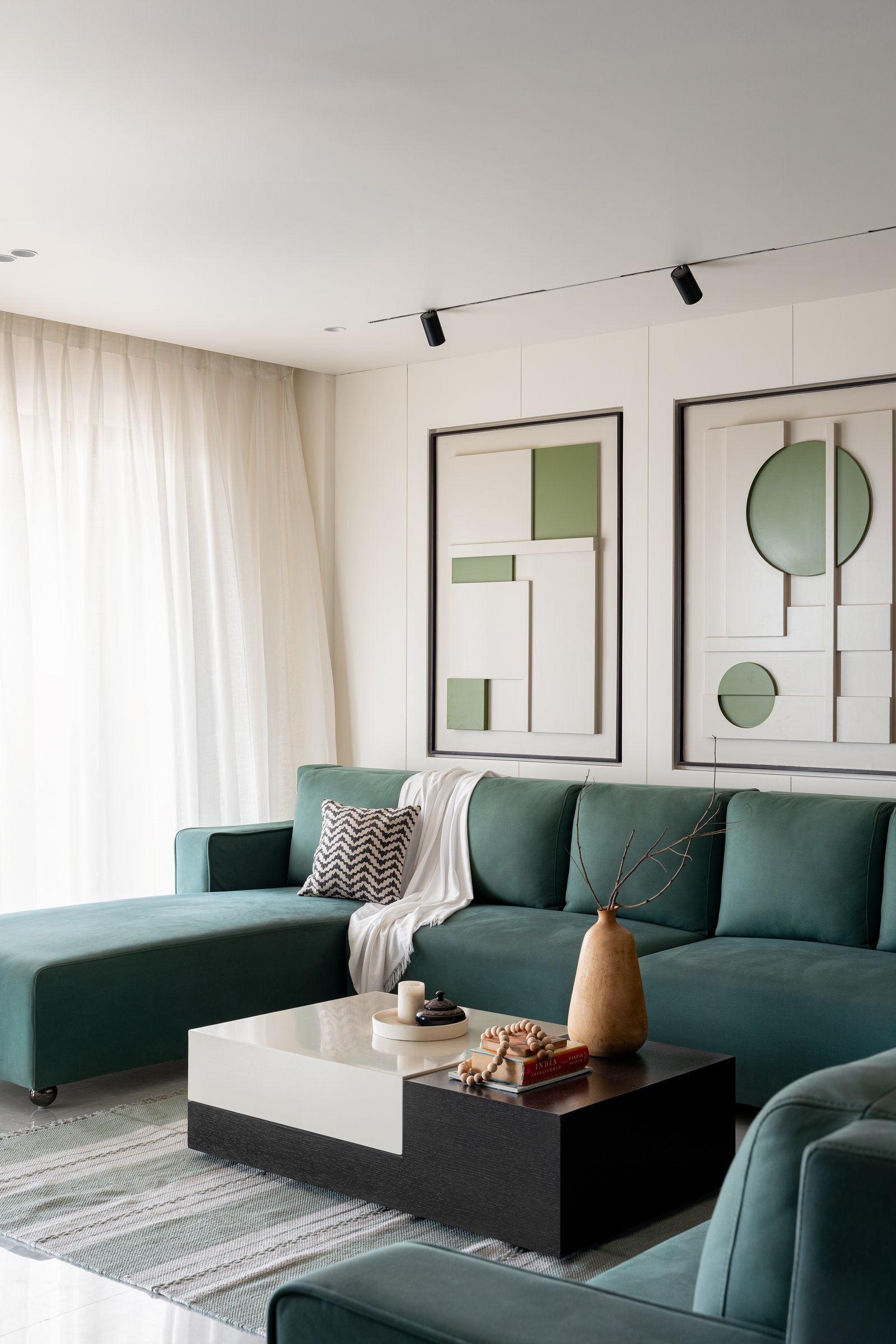 Sheer drapery filters daylight into the seating area, where the stacked coffee table holds the floor without competing for attention