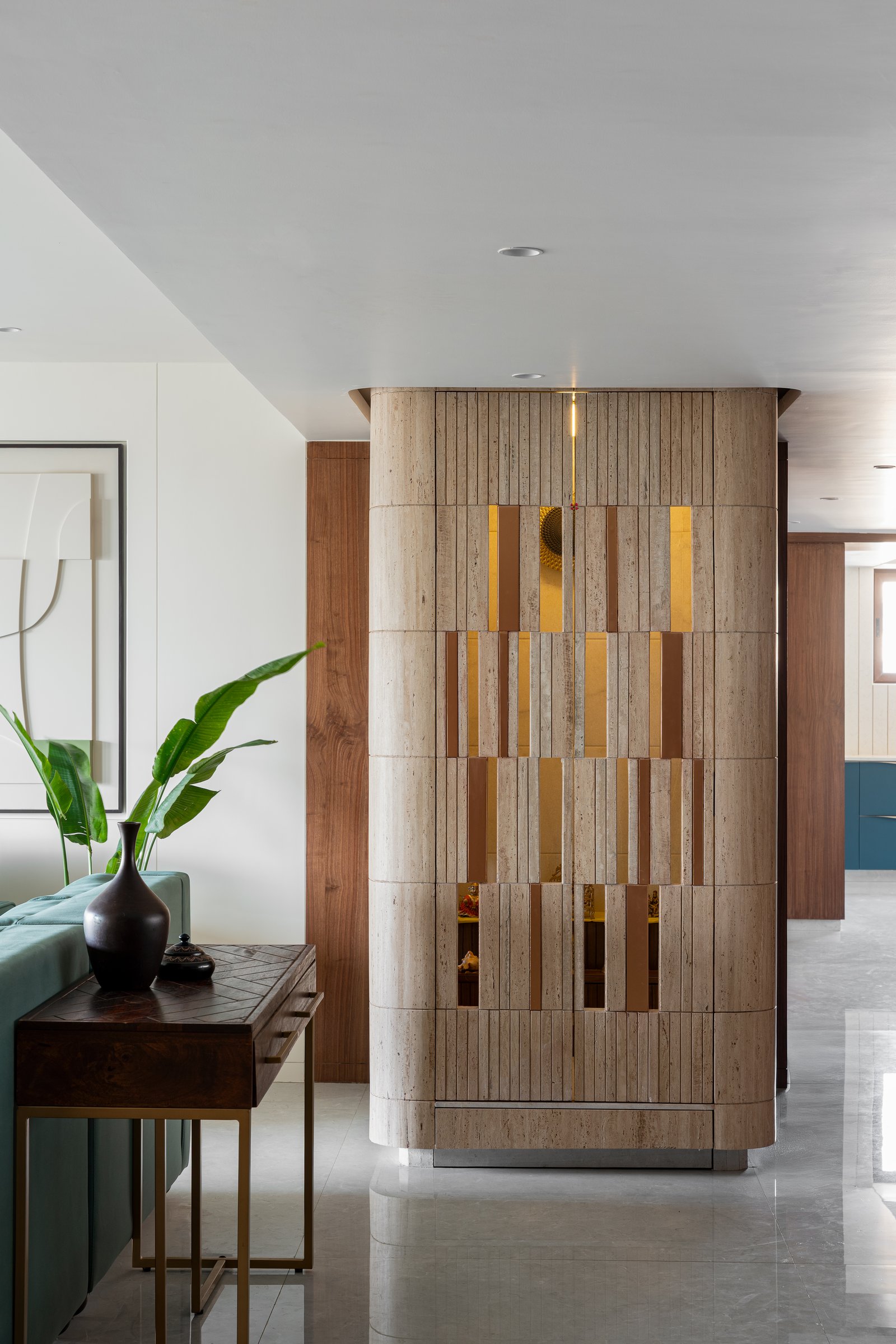 The temple, a sculpted travertine column with brass-lined inserts, stands as the home's luminous centrepiece