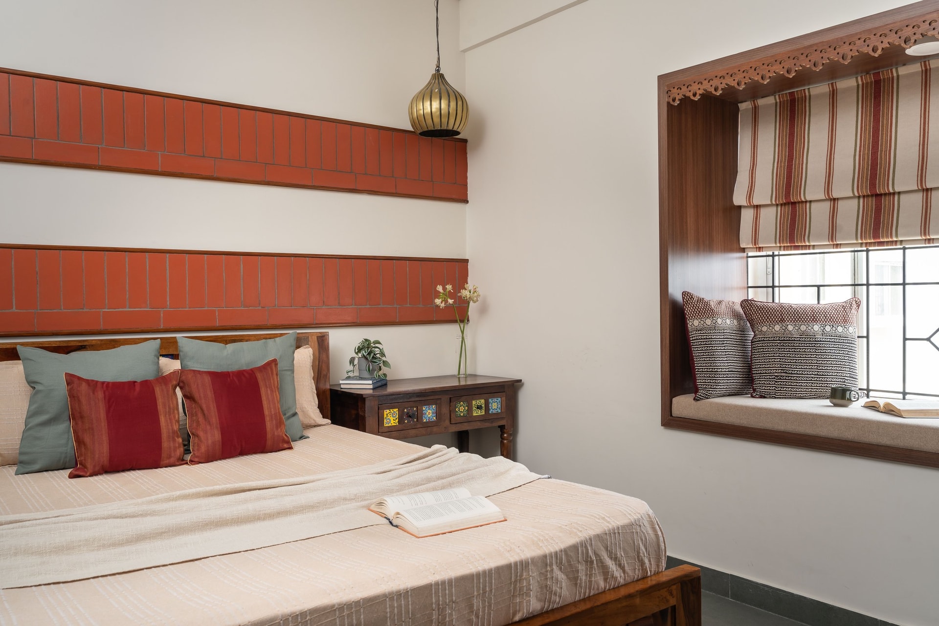 The guest bedroom, where banded terracotta brick and a turnip-silhouette brass pendant introduce a sharper material register