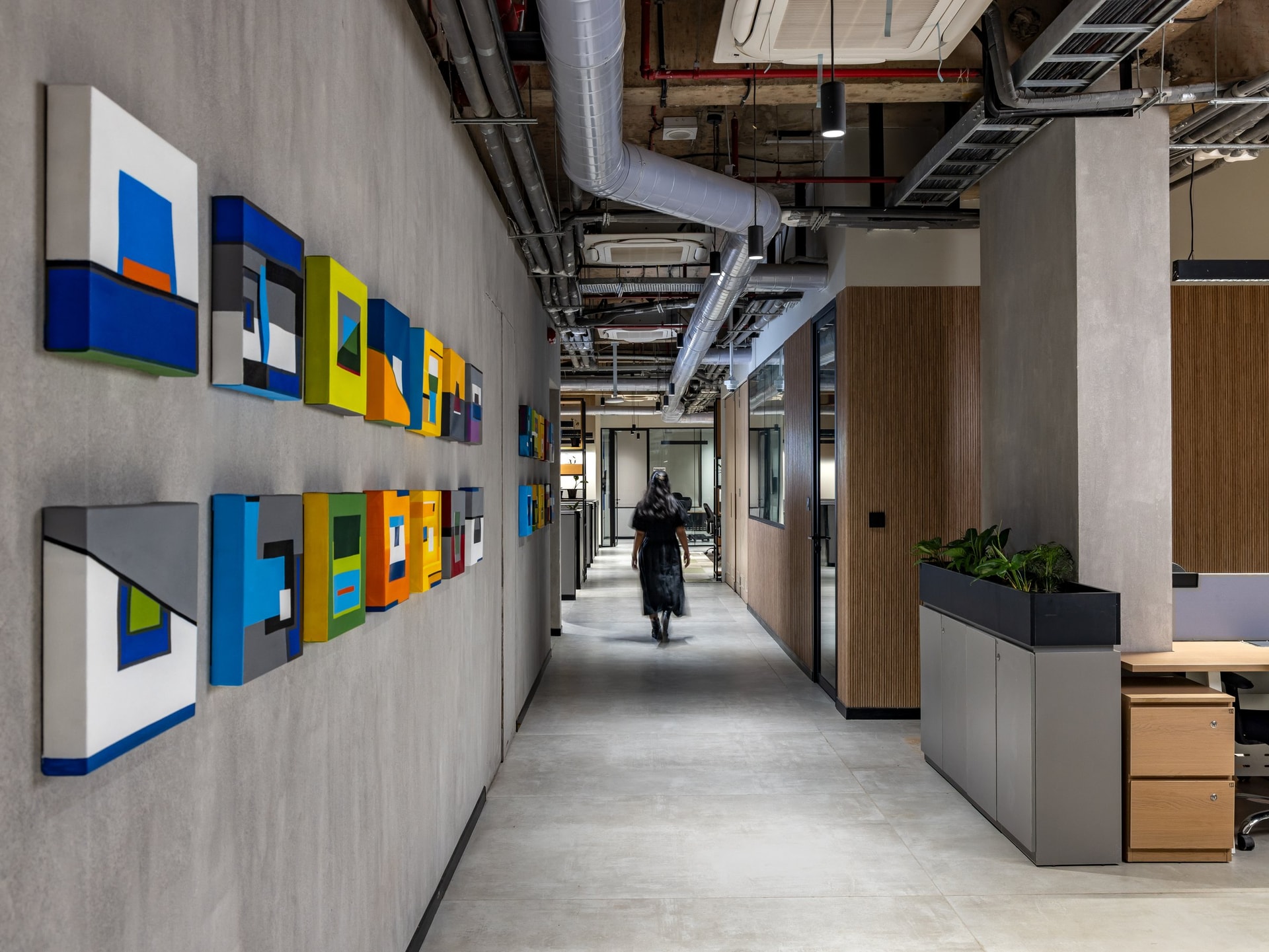 A corridor turned gallery, where small abstract canvases punctuate the concrete wall