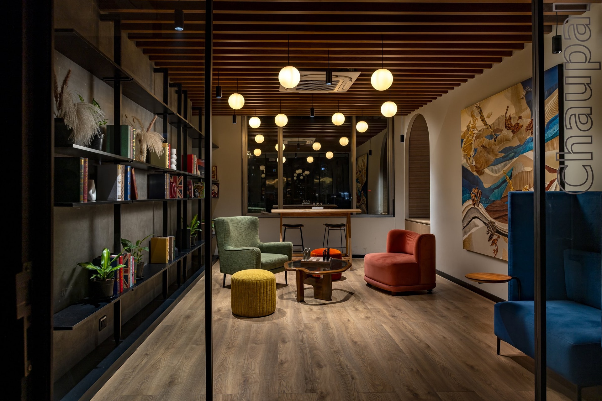 Chaupal, the breakout zone, where velvet seating gathers beneath a constellation of glass globe pendants