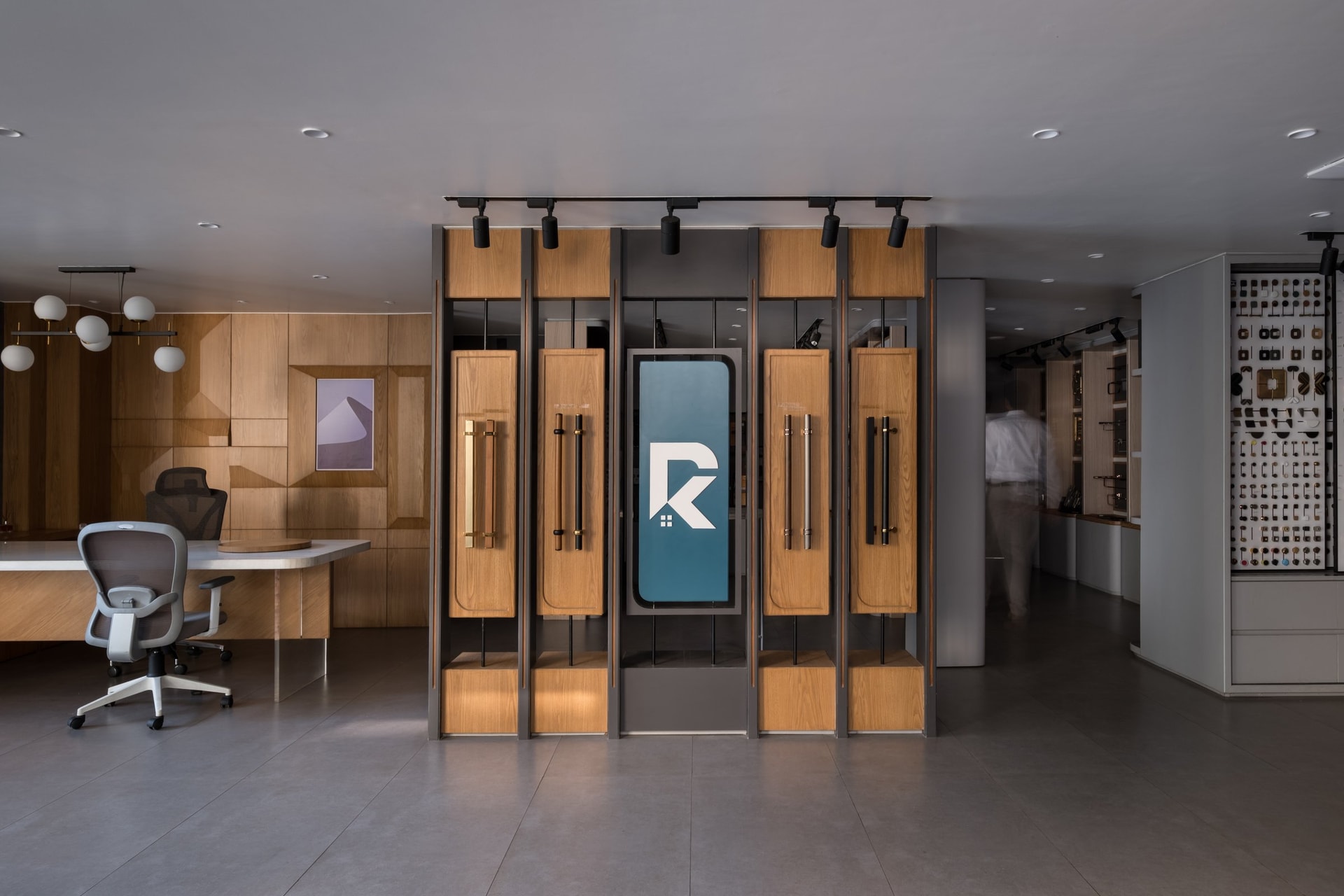 A freestanding display rig steps forward from a faceted oak wall, anchoring the showroom's branded signature near the consultation desk