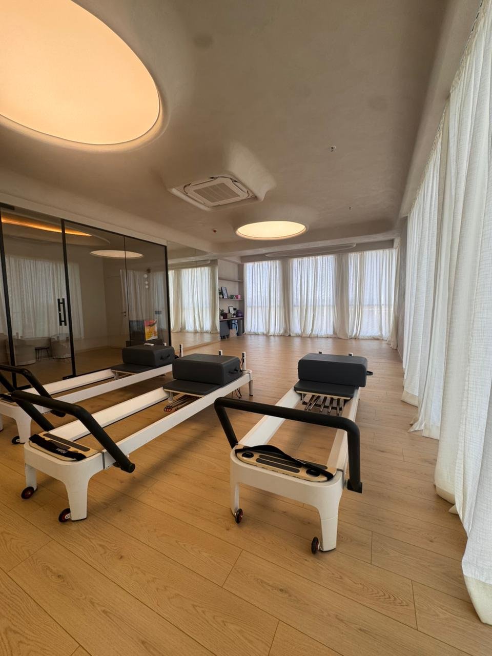 The mirrored wall multiplies the volume and supports postural alignment, while every other surface holds its restraint