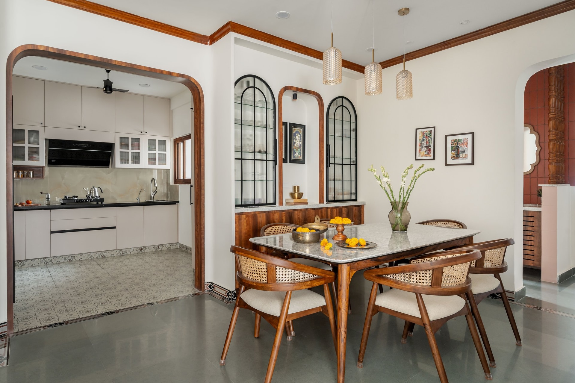 The dining table and its arched reeded-glass crockery niches, where Pattachitra miniatures hide between the cabinets