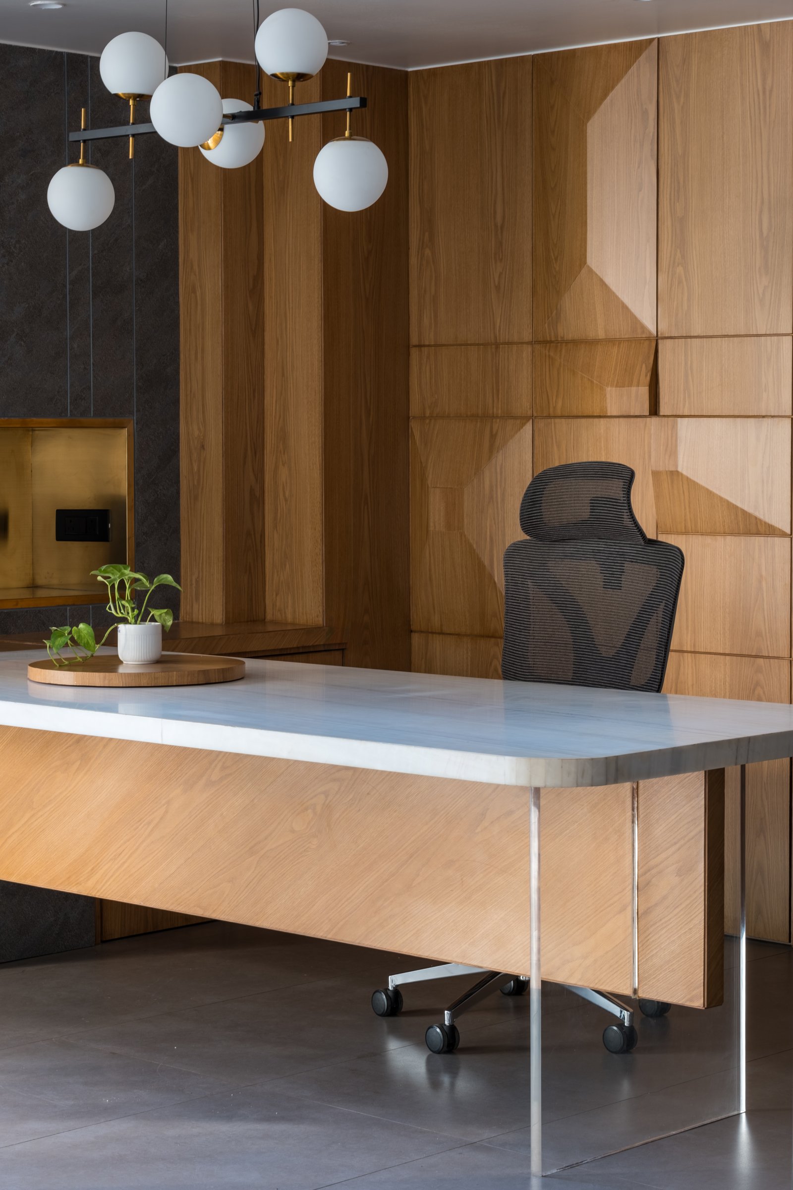 The principal cabin: a marble-topped desk against a faceted oak wall, the project's thesis distilled into a single composed room