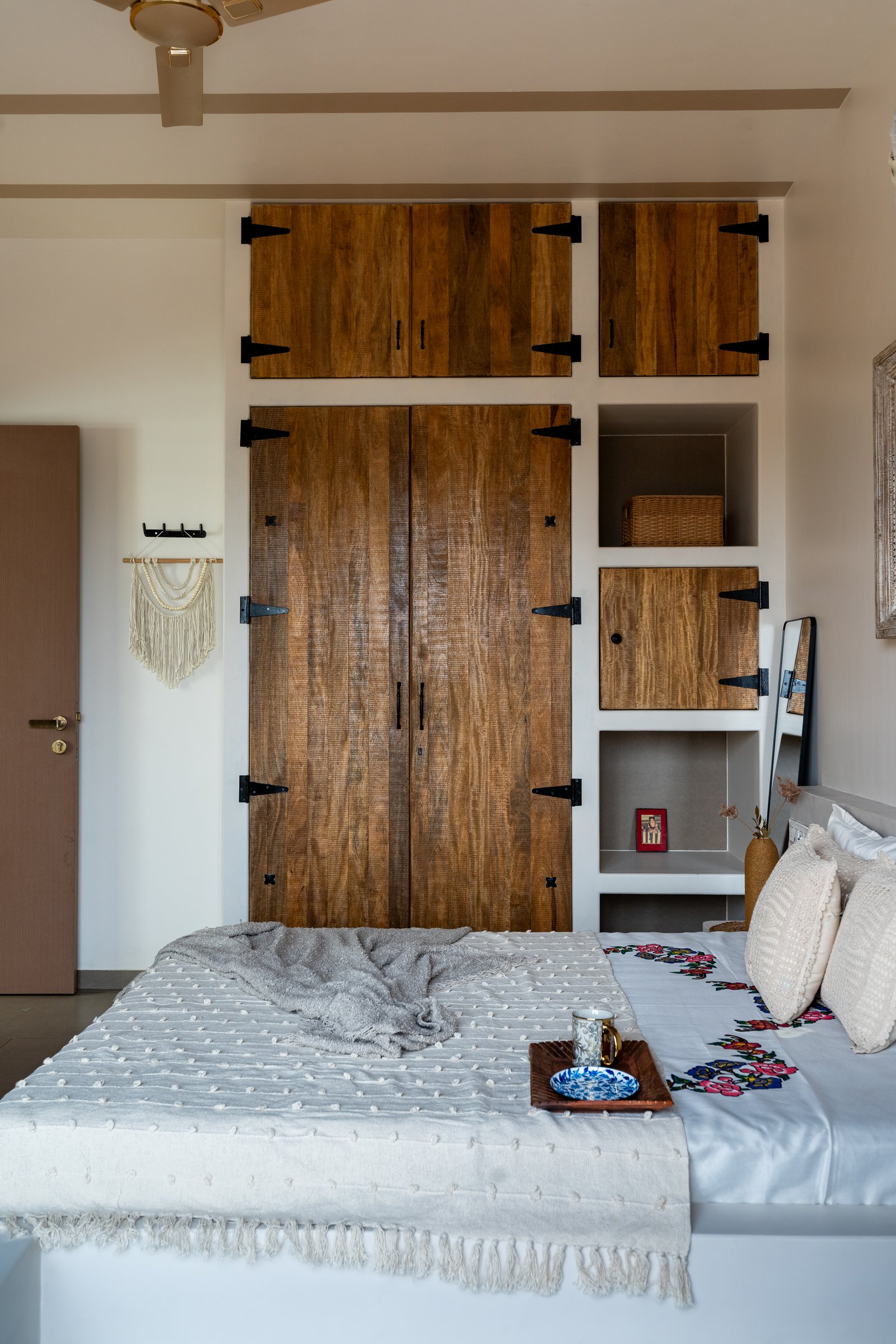 The second bedroom, where a roughly sawn wood storage wall with iron strap hinges references older Rajasthani granaries