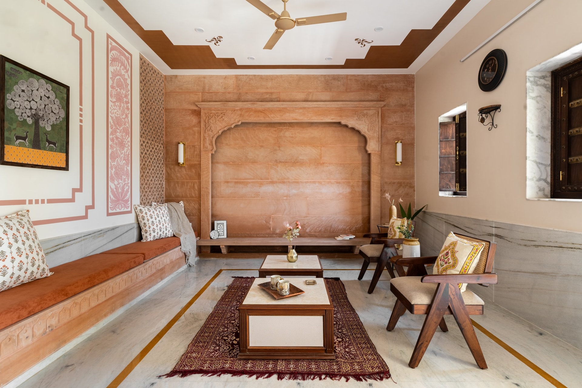 The living room, where a carved sandstone arch and terracotta velvet seating establish the home's central material argument