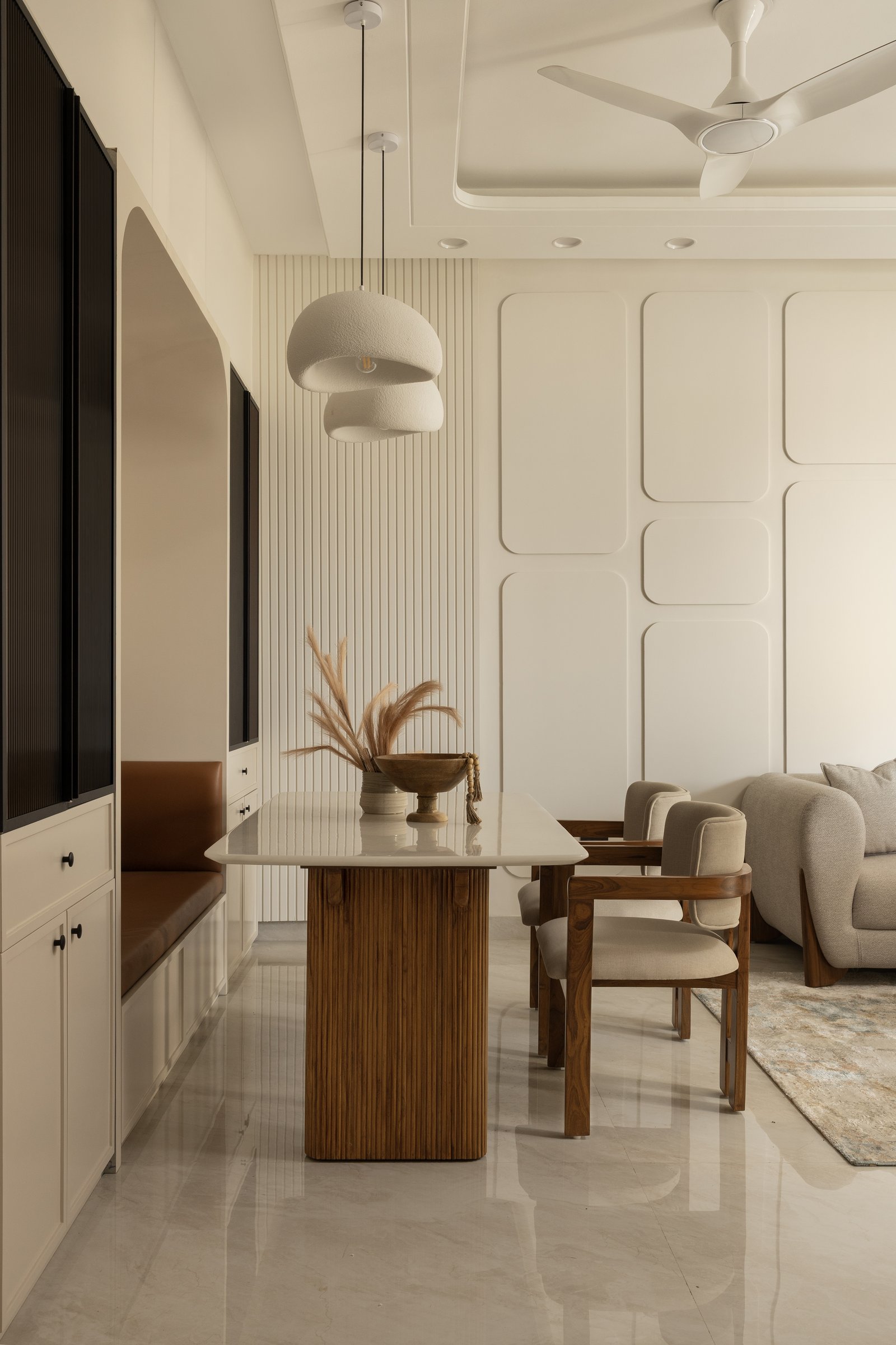 The dining table on its reeded pedestal, with a built-in banquette doubling the space as a reading corner