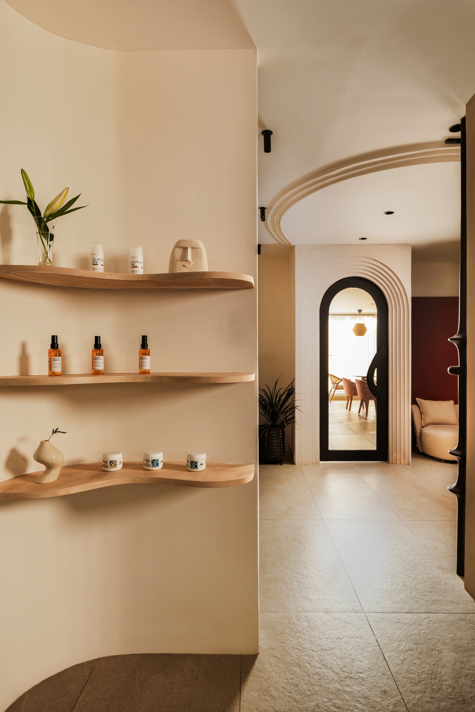 The threshold between retail and café, framed by a layered arched portal and undulating shelves