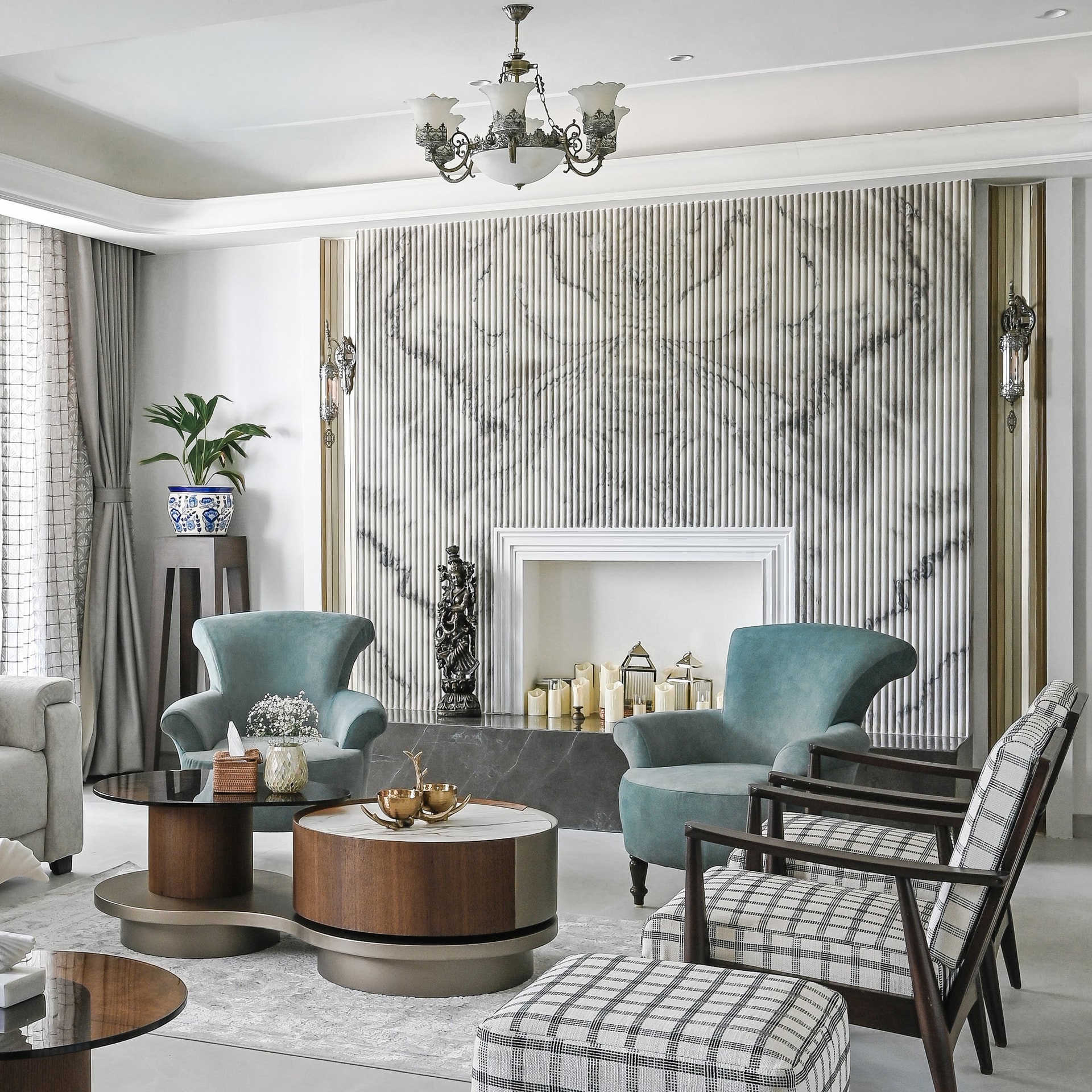 The fluted marble feature wall: the room's single theatrical gesture, anchored by two teal velvet armchairs