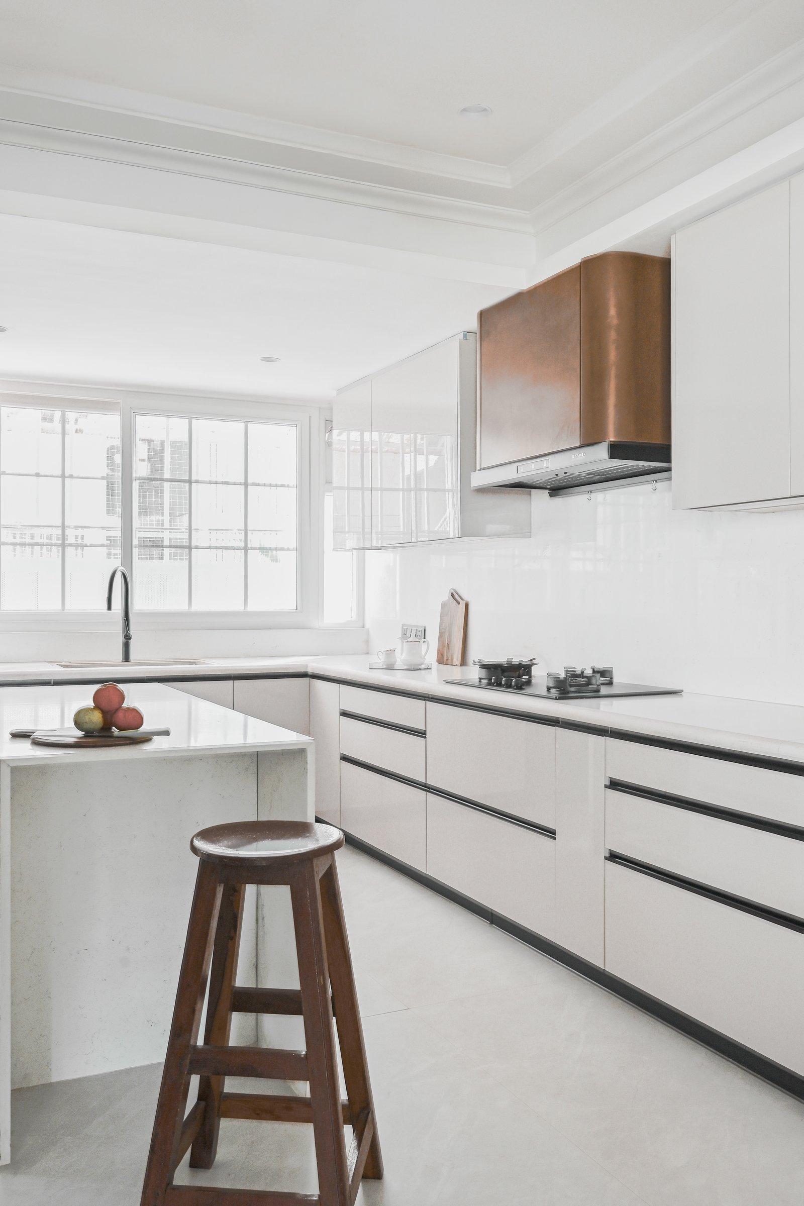 The kitchen's quietest gesture: a copper-clad chimney hood lifting glossy white cabinetry into something crafted