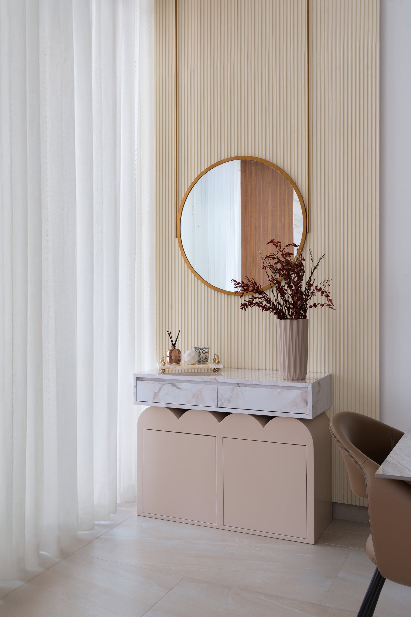The foyer console, where a ribbed ivory wall and a scalloped blush base establish the home's central grammar