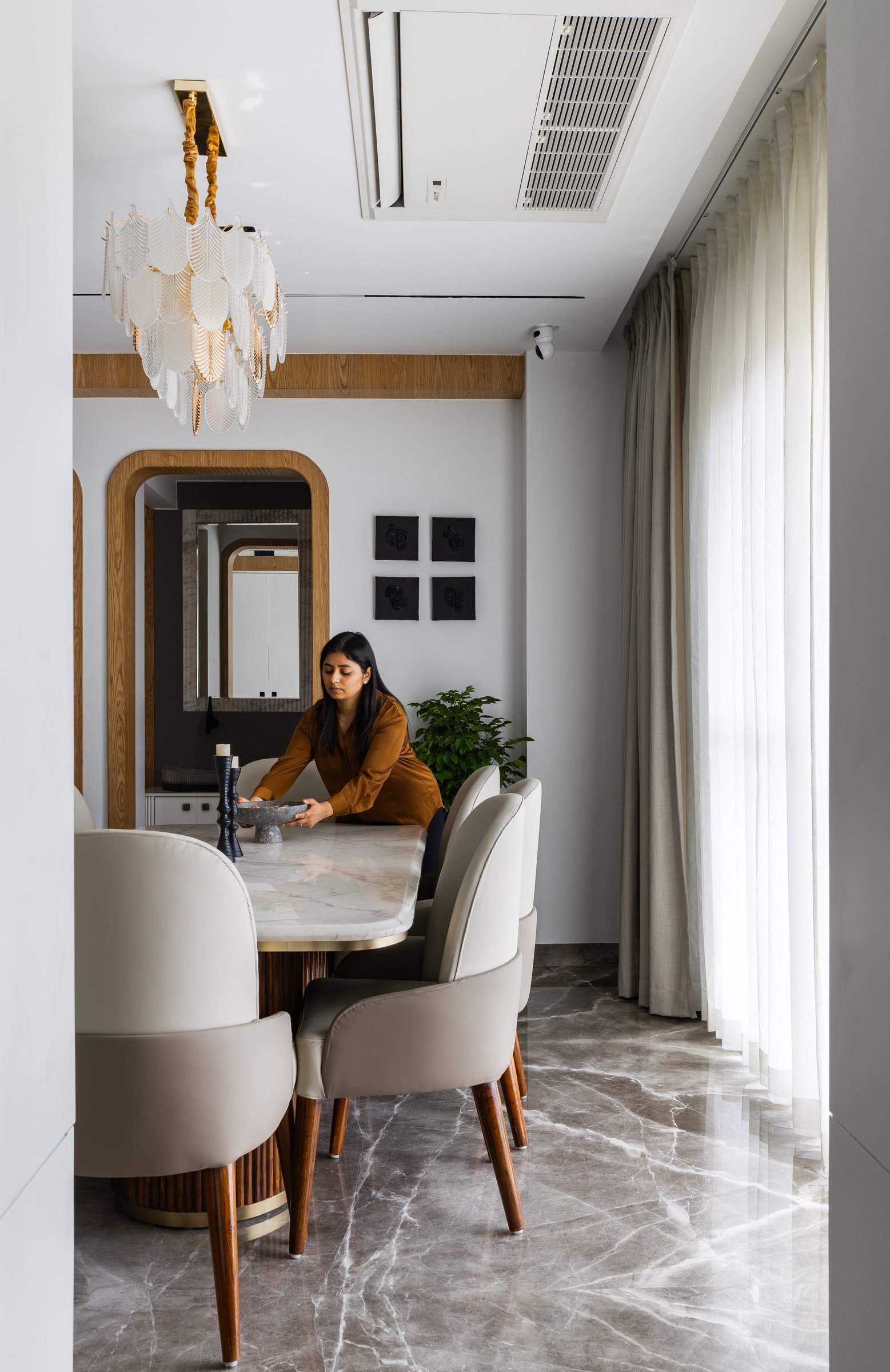 The dining seen lengthwise, where an arched mirror in a wooden frame doubles the room's depth