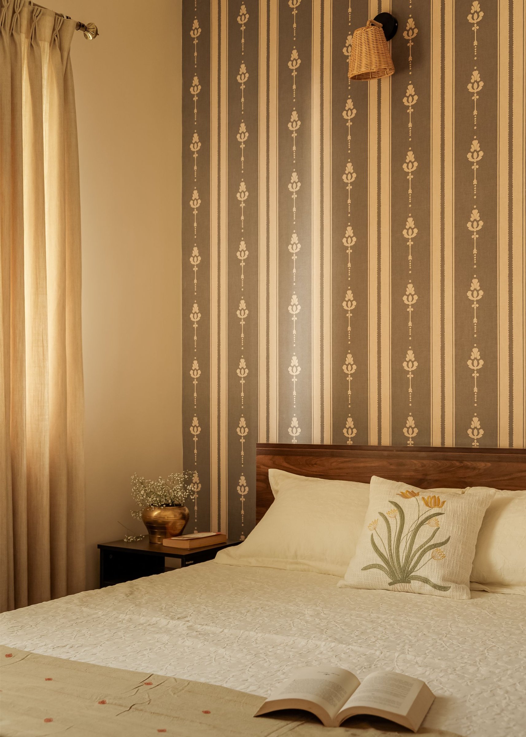 The guest bedroom, where a striped patterned wallpaper rises behind a low wooden headboard