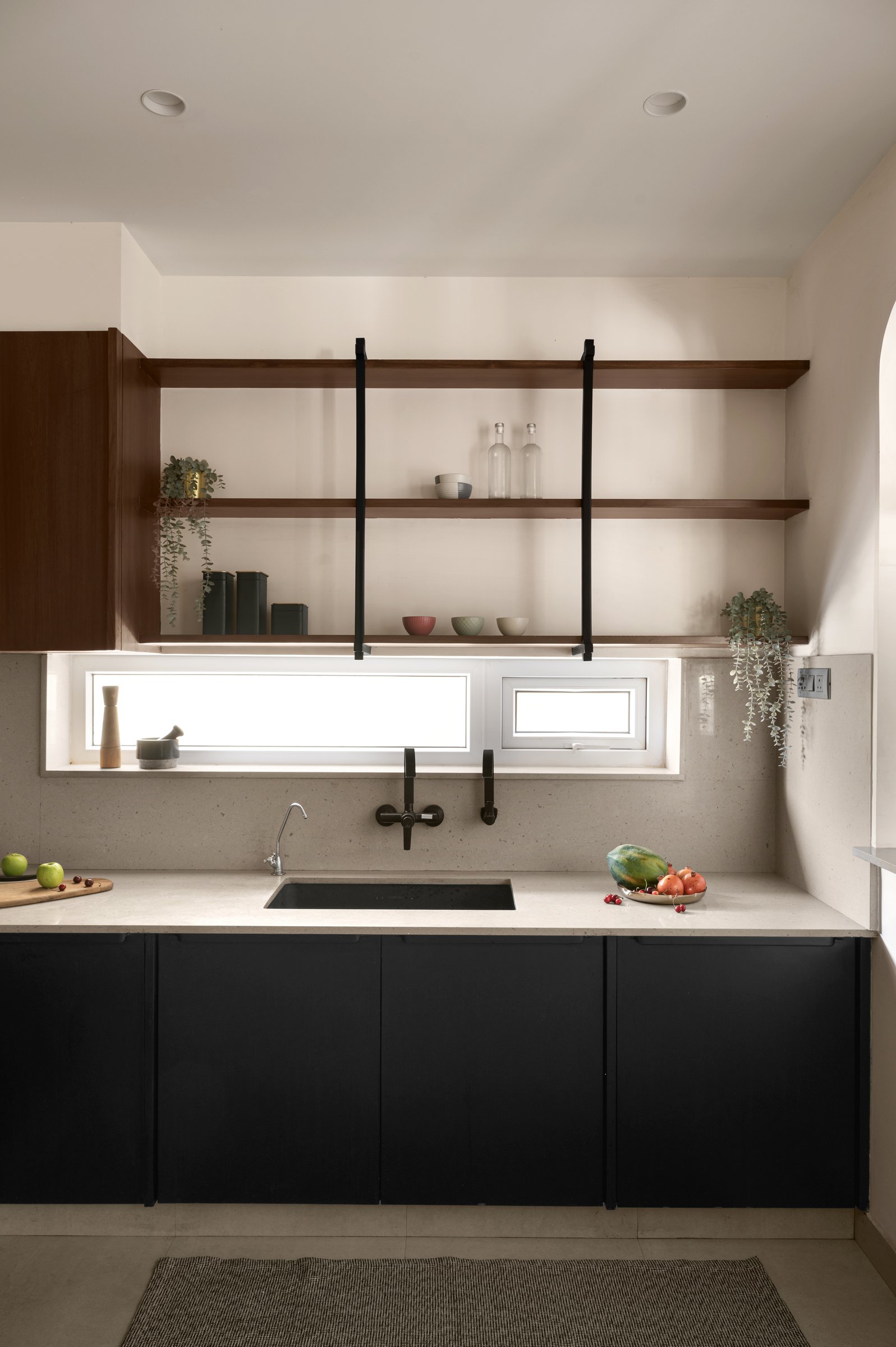 The kitchen's second run, with black open shelves suspended on slender straps in front of a ribbon window