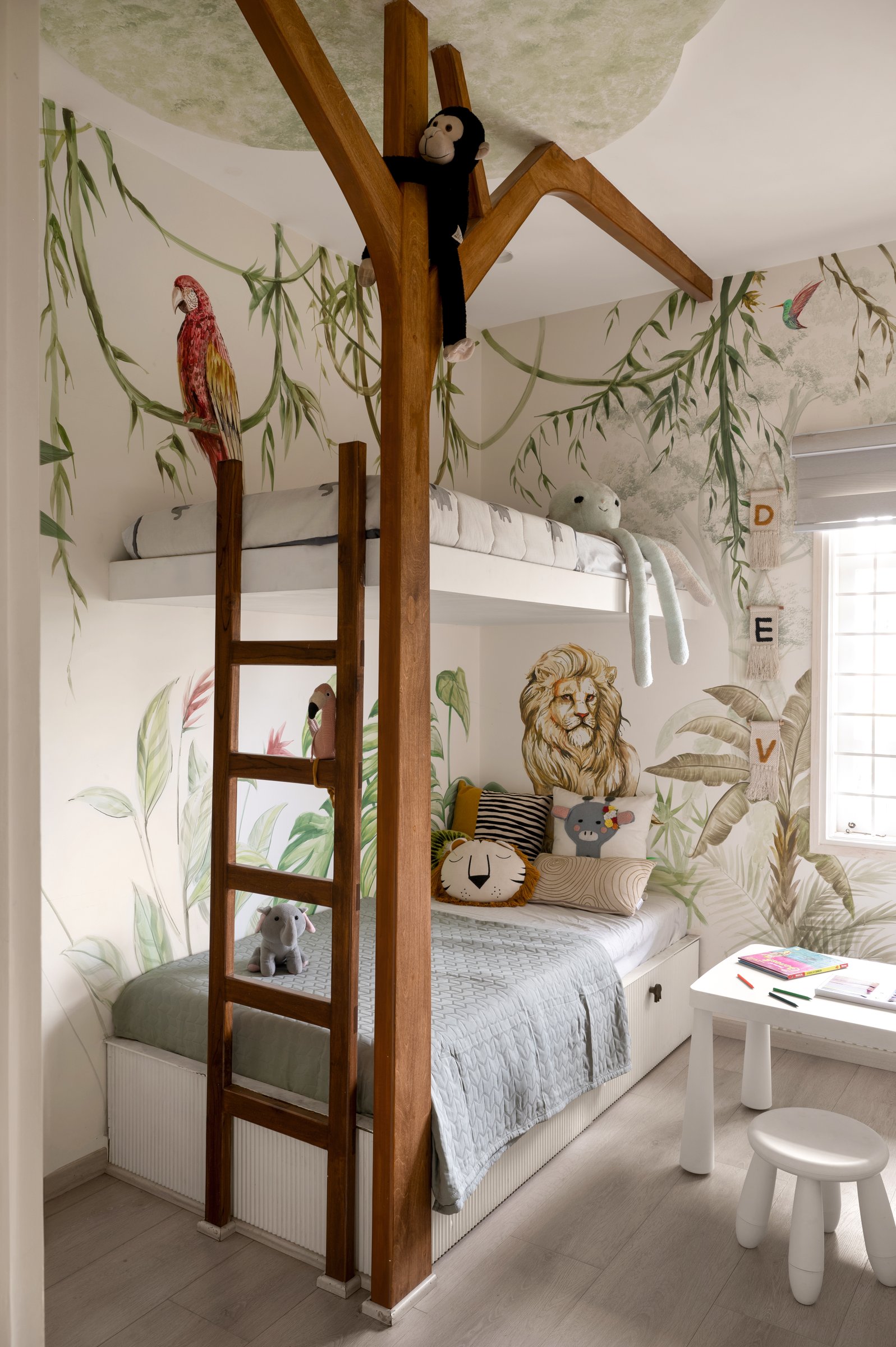 The son's bedroom, with a teak bunk bed shaped like a tree and a hand-painted jungle mural wrapping the walls