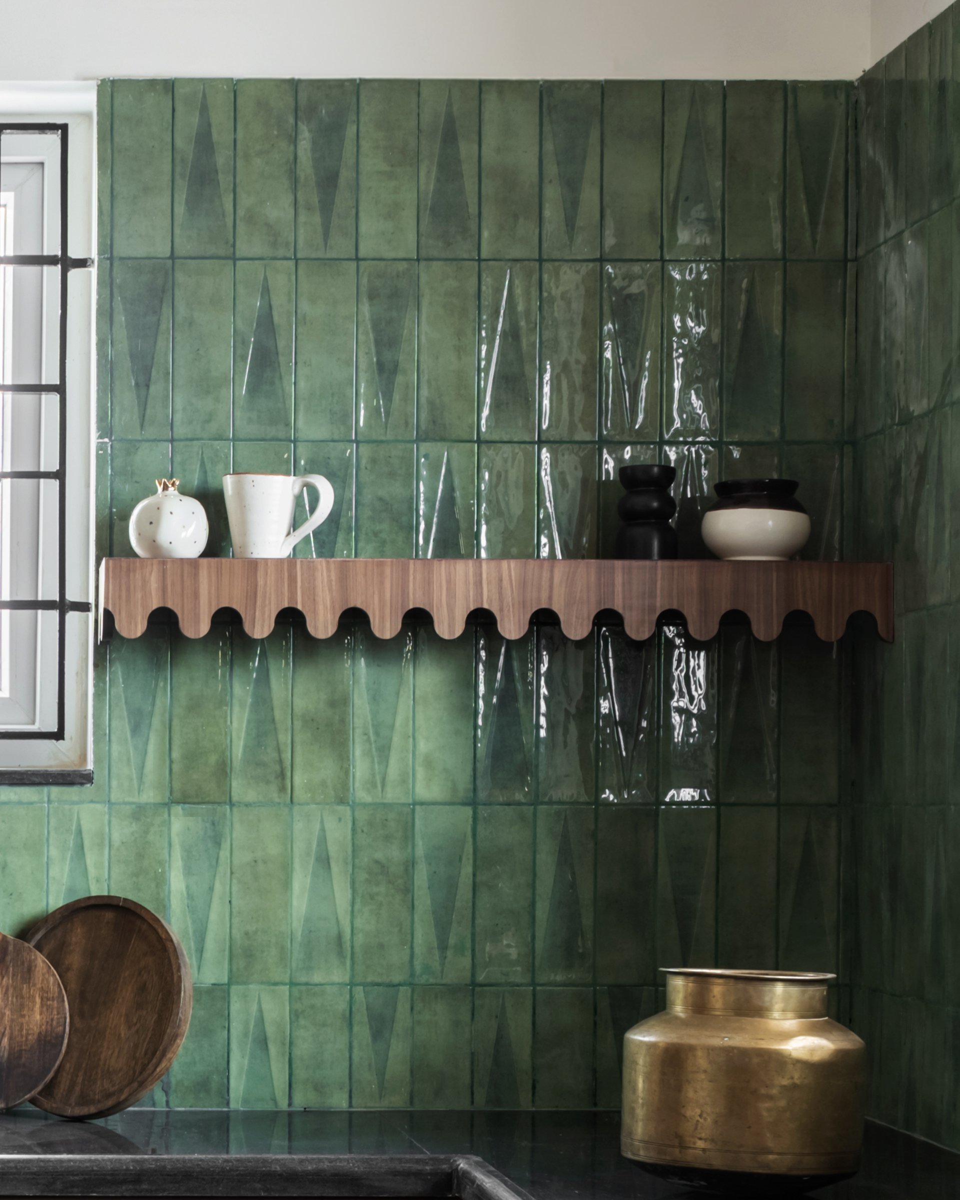 The scalloped wooden shelf against the green tiled wall, a small piece of joinery that rhymes across rooms