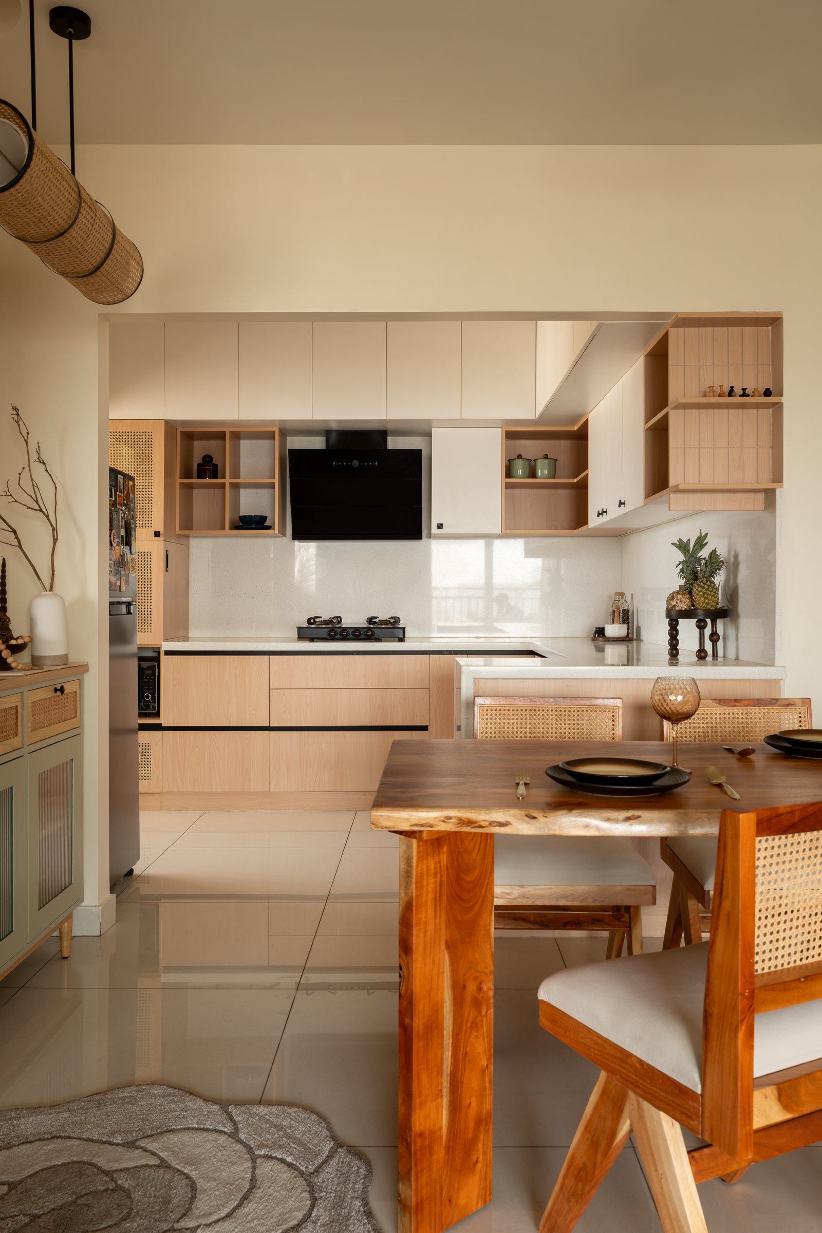The dining area, anchored by a live-edge wooden table and cane-backed chairs, opening directly onto the kitchen beyond