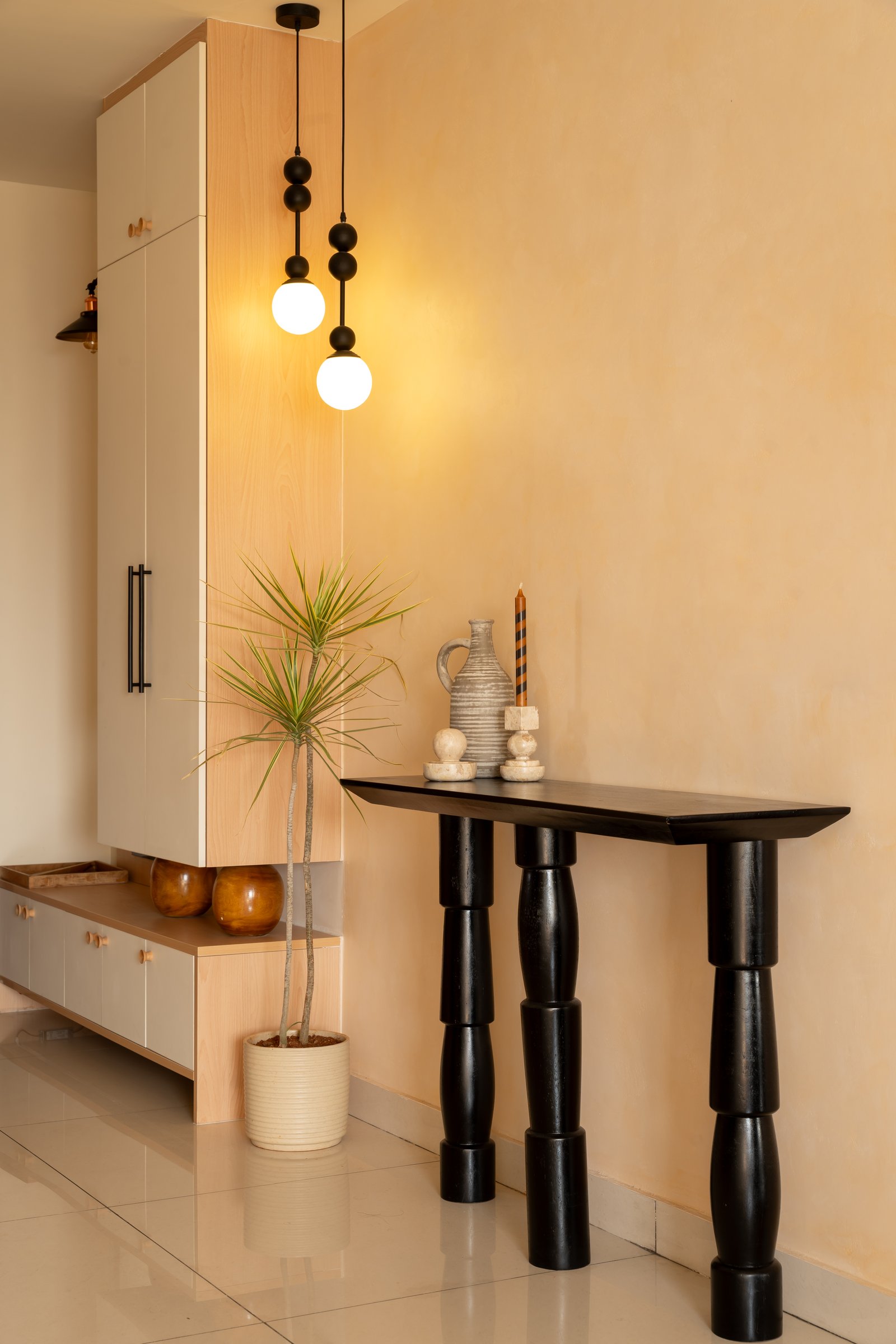 The foyer, where a sculptural black console and warm globe pendants set the home's grammar of restraint