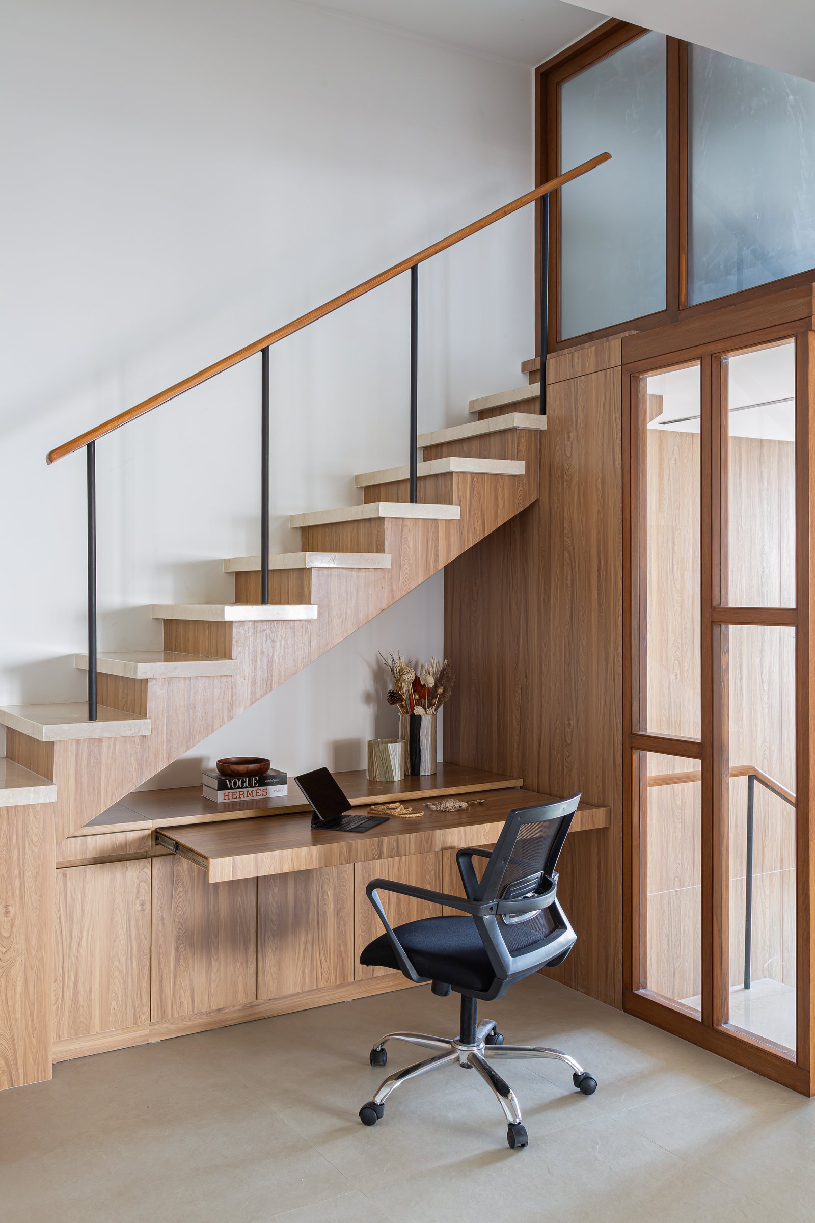 The under-stair workstation, where a pull-out wood desk and integrated cabinetry transform the residual volume into a functional nook
