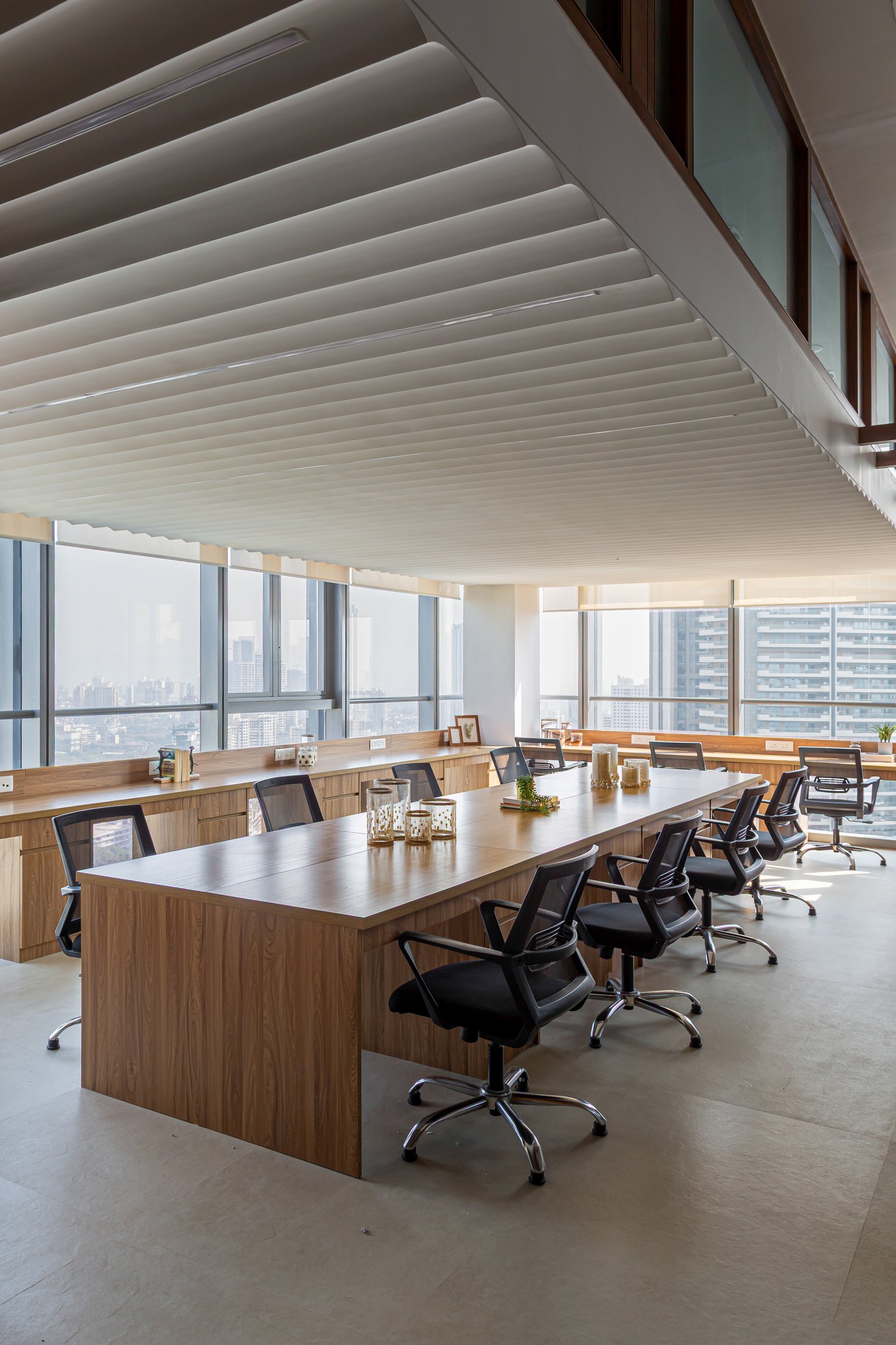 The primary workspace on the upper floor, where a long communal worktable runs beneath a fluted plaster ceiling and a continuous wood credenza traces the perimeter