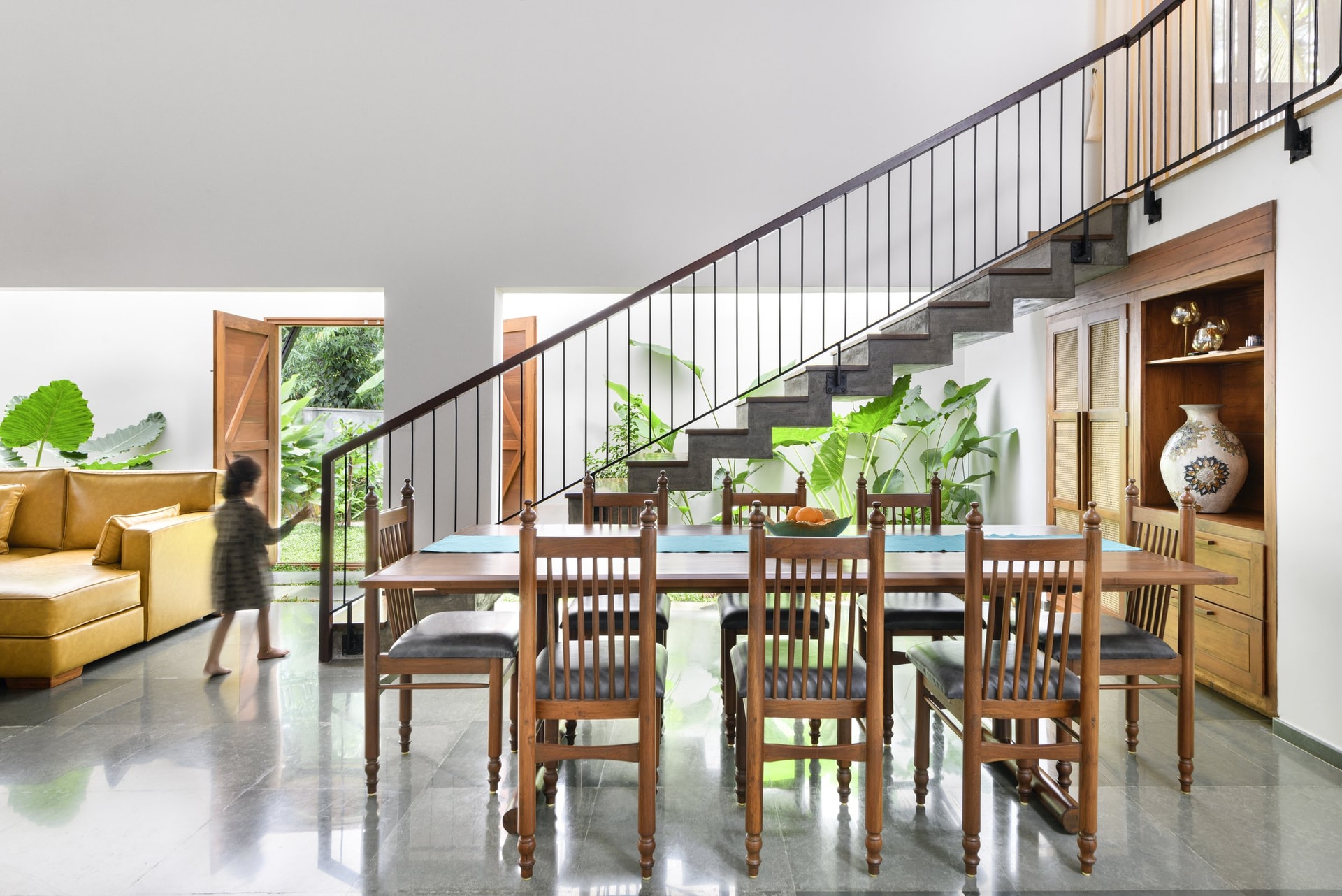 The dining table parallel to the cantilevered concrete staircase, with a glimpse of the back garden