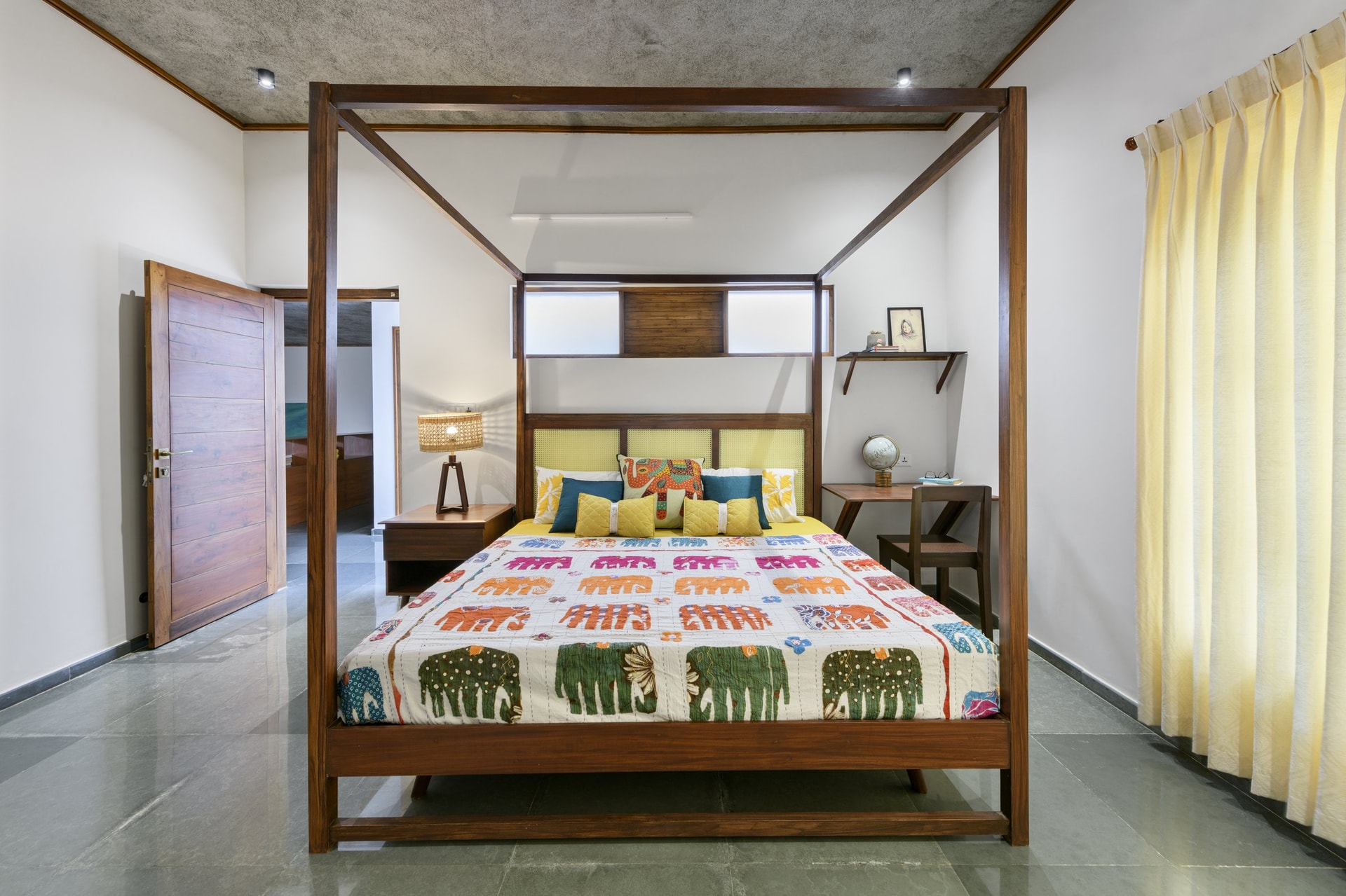 A second bedroom with a four-poster wooden bed and a printed throw introducing a graphic note