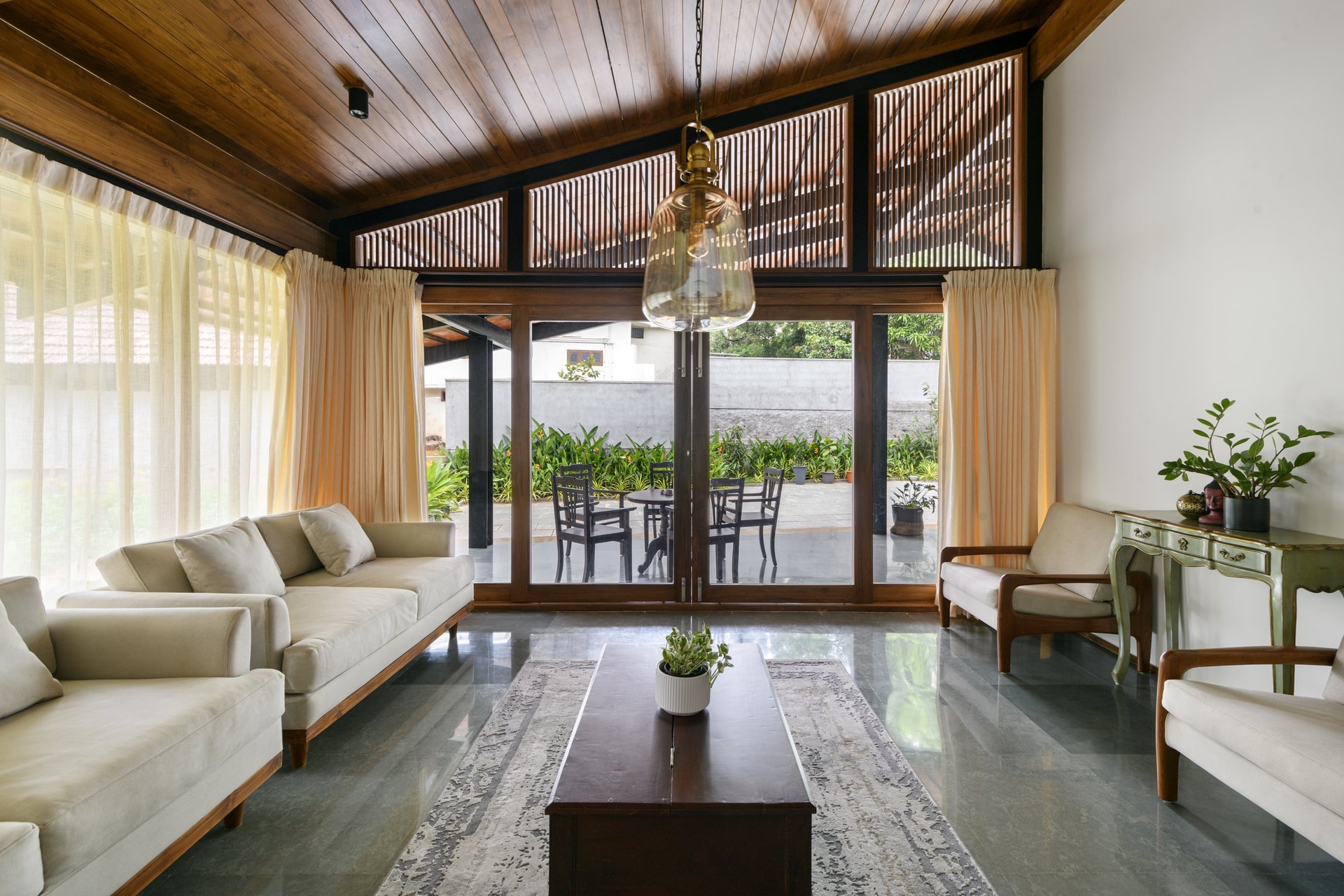 The formal living room, where a high pitched wooden ceiling and clerestory battens sit above pale upholstered sofas