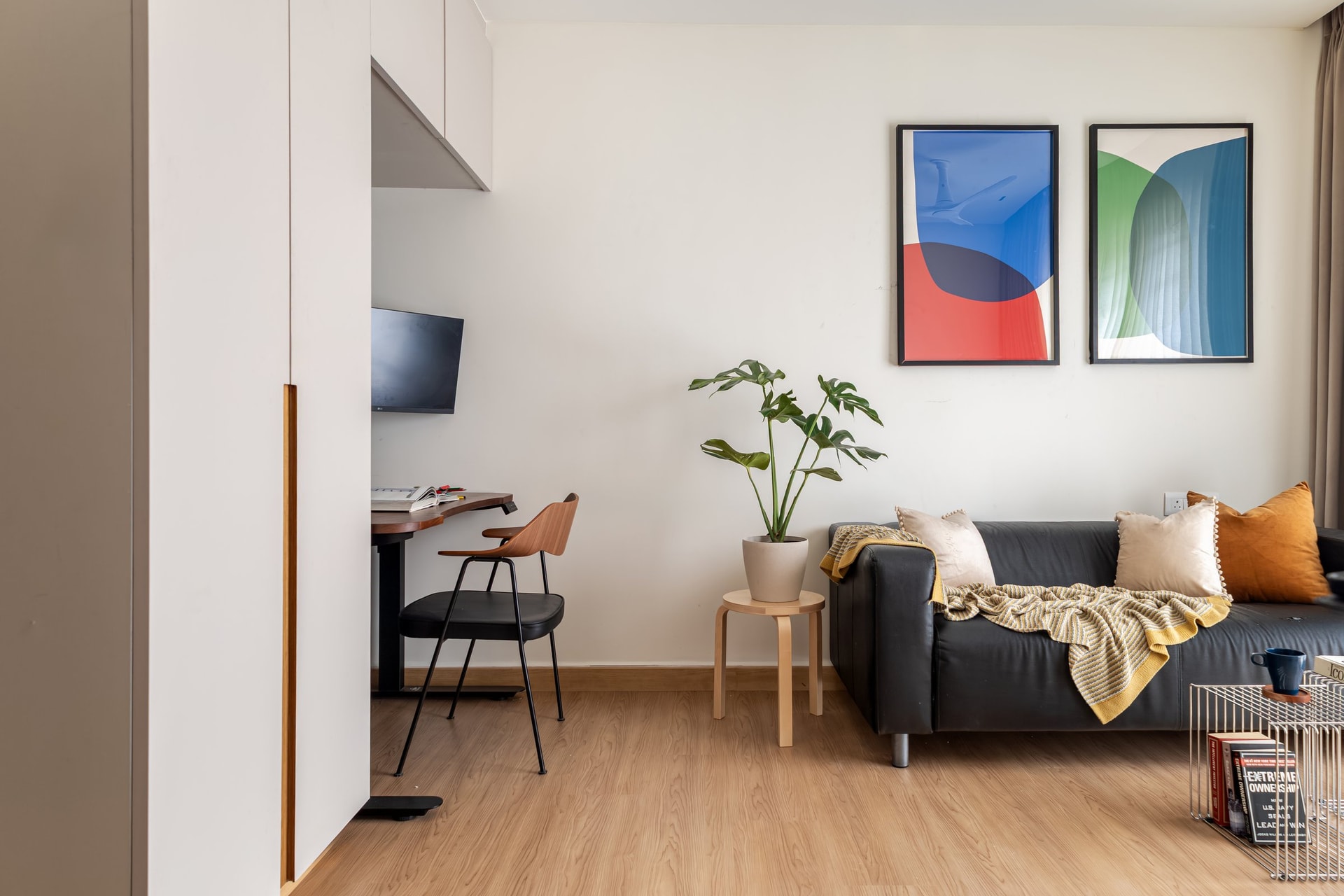 The third bedroom, reconfigured as a workspace, with a leather daybed and a pair of saturated abstract prints