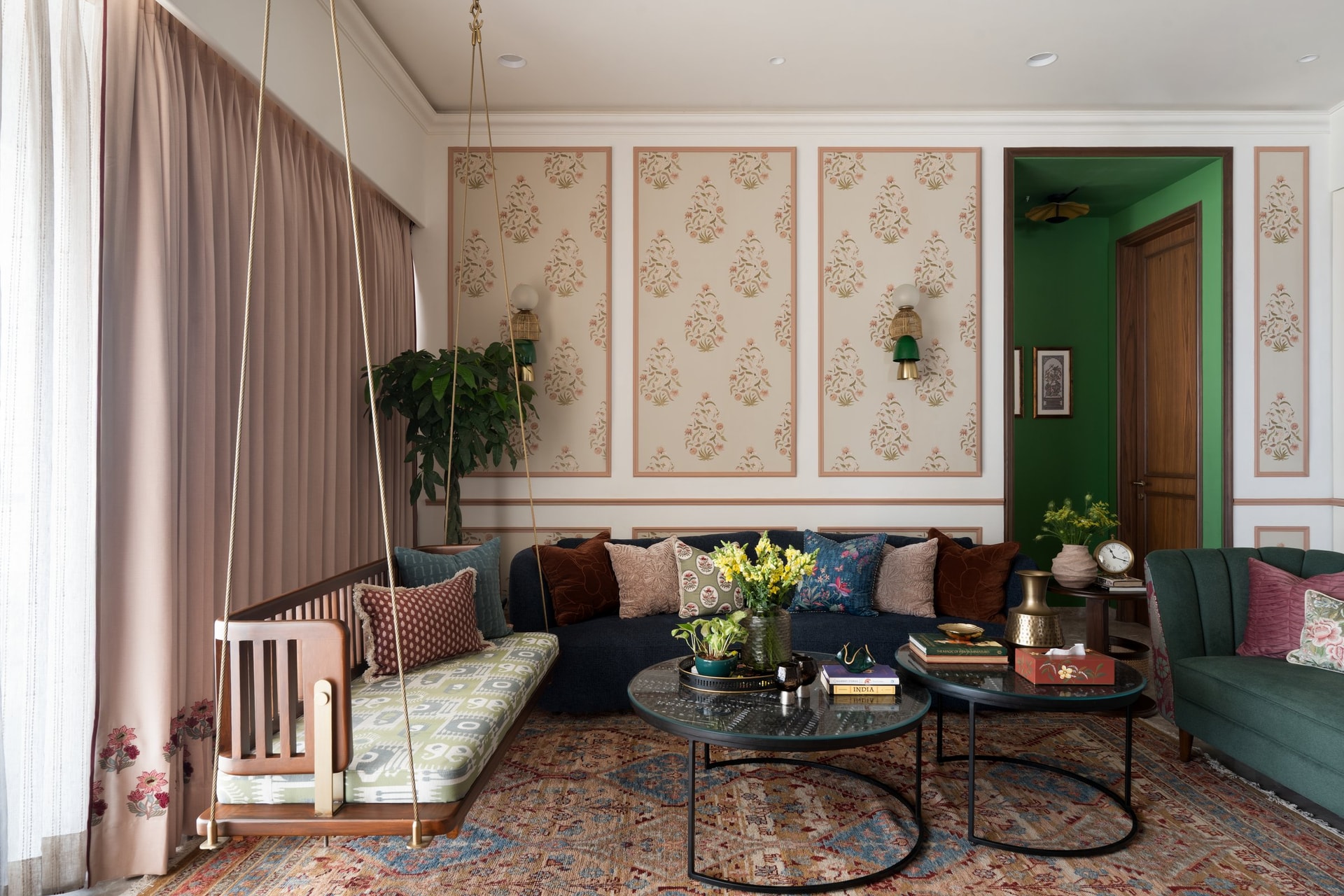 The living room, where a slatted swing and a deep blue sofa sit against panelled walls of floral buti print